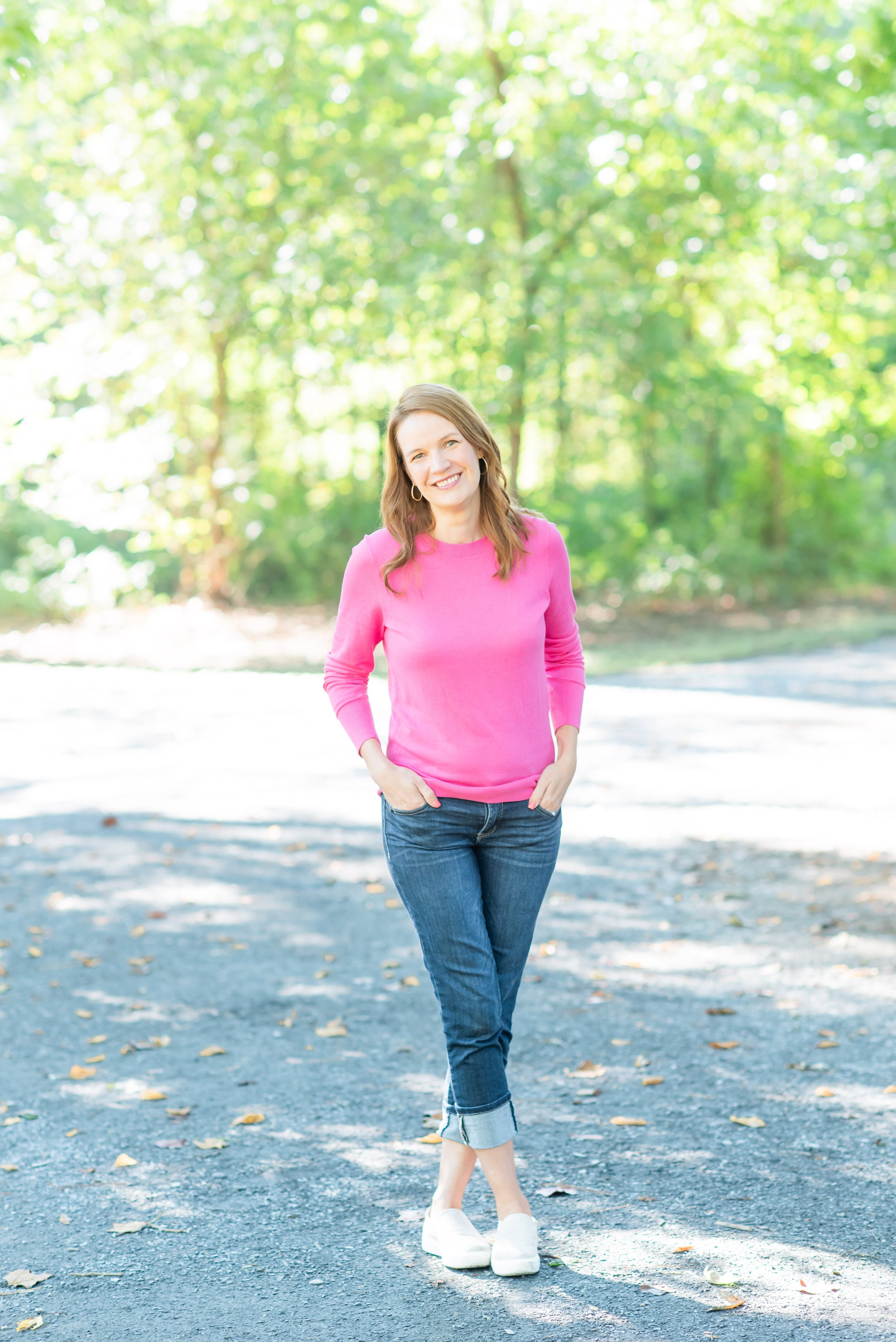 photographer walking with her hands in pockets wearing a pink sweater