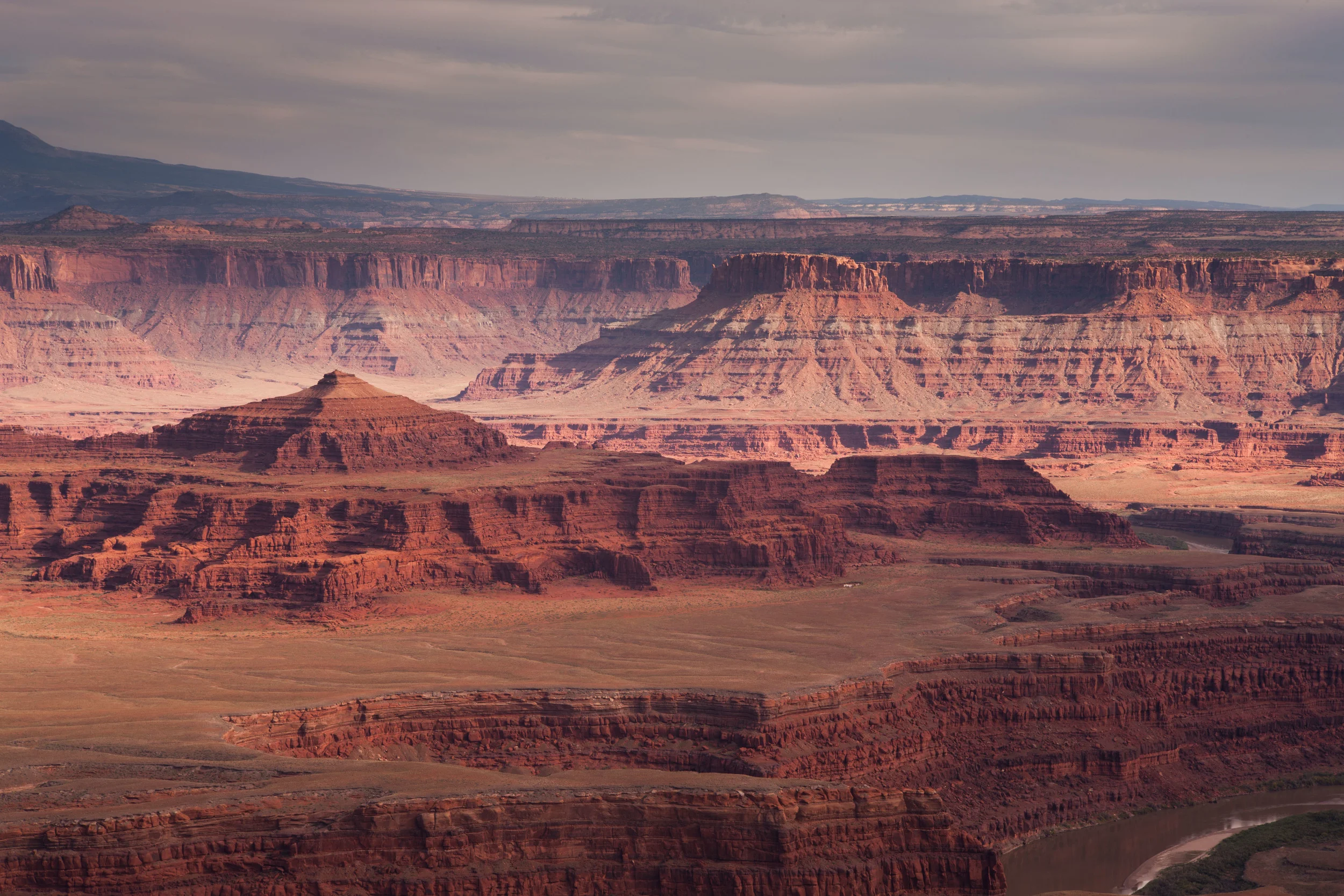  A pinhole photo of pink and brown canyons in the near and middle distance with a gray cloudy sky.  