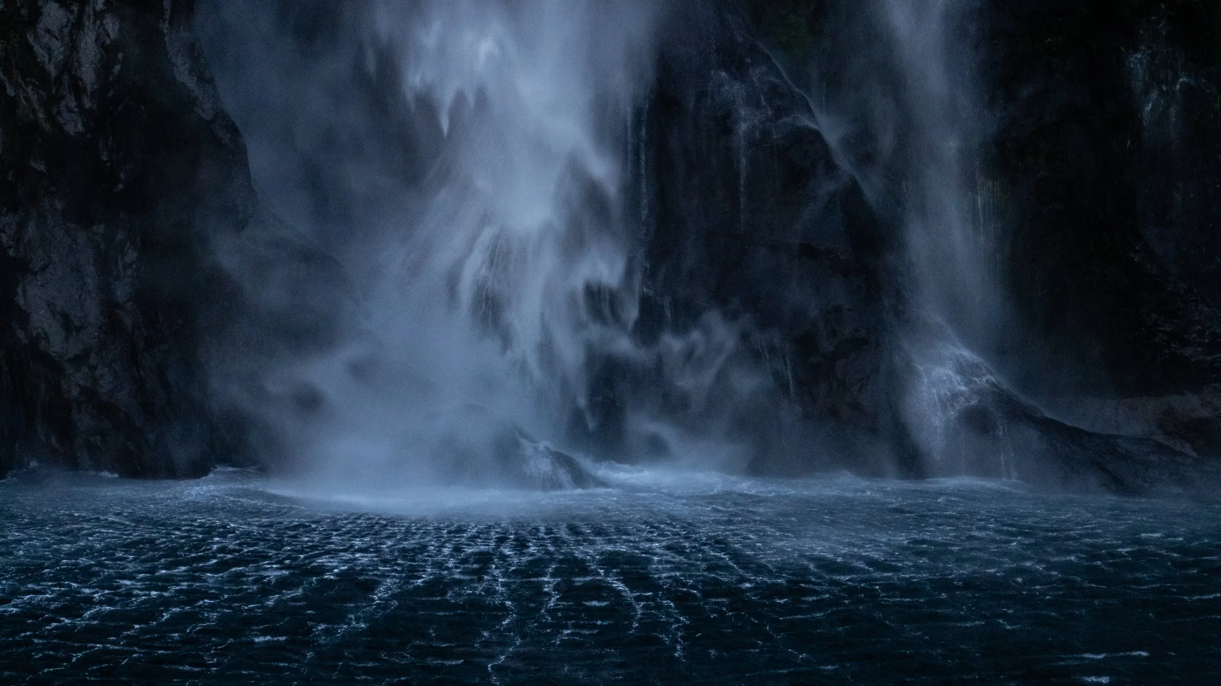  Waterfall in the shade. Lines appear as a grid in the water. The colors are cool blue and black.  