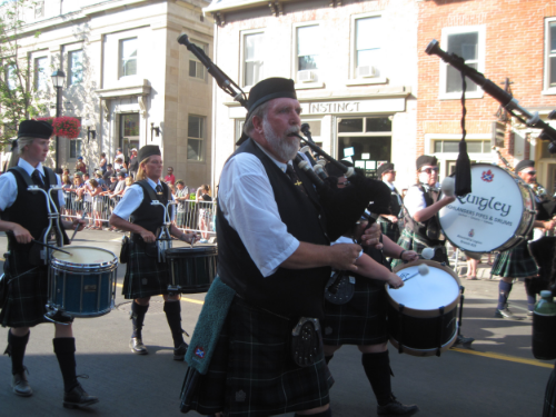 Before the race begins, a pipe band leads a procession of racers through the streets of Perth, Ontario.