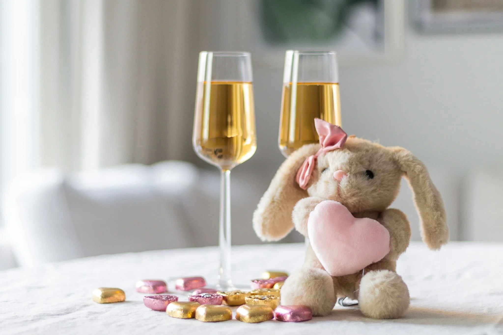 Kaksi skumppalasia limulla, suklaasydämiä ja pehmopupu pitämässä sydäntä