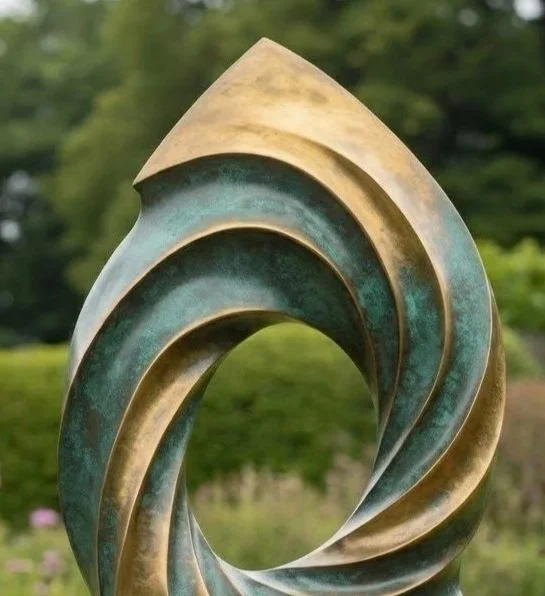 A modern, abstract bronze sculpture with a swirling, wave-like shape set outdoors with trees and bushes in the background.