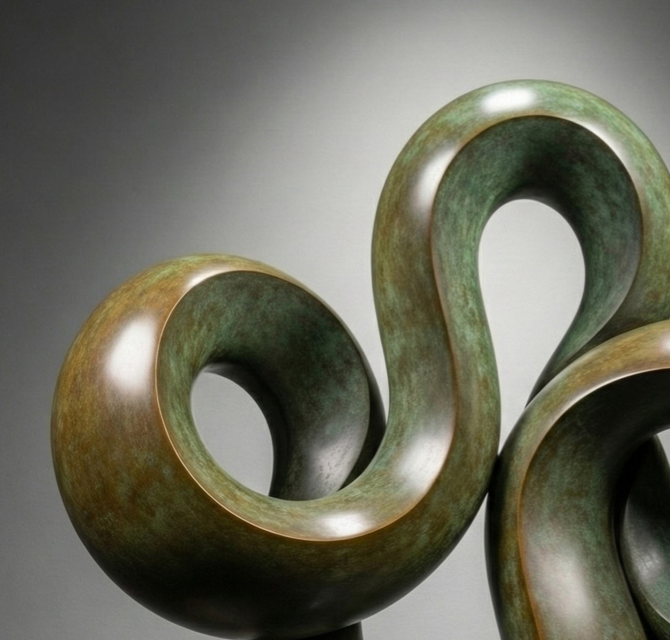 A modern sculpture composed of smooth, rounded, metallic and greenish elements forming an abstract, intertwined shape, mounted on a rectangular base against a plain background.