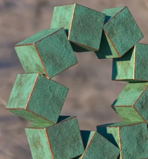 A vertical sculpture made of connected green, weathered metal cubes in a circle, balanced on a single cube base, outdoors on a sunny day.