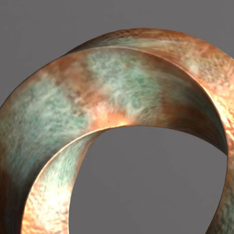 A close-up of a large, bronze-colored metallic ring sculpture positioned on a black pedestal against a plain gray background.
