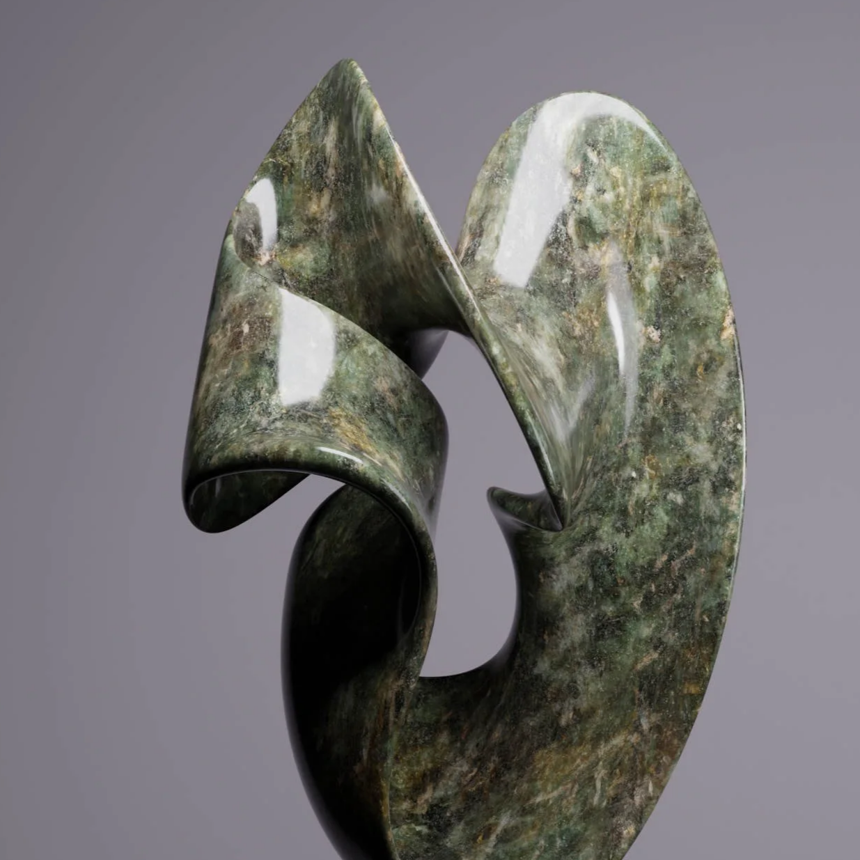A modern sculpture with flowing, abstract forms made of polished greenish marble, mounted on a black pedestal against a plain gray background.