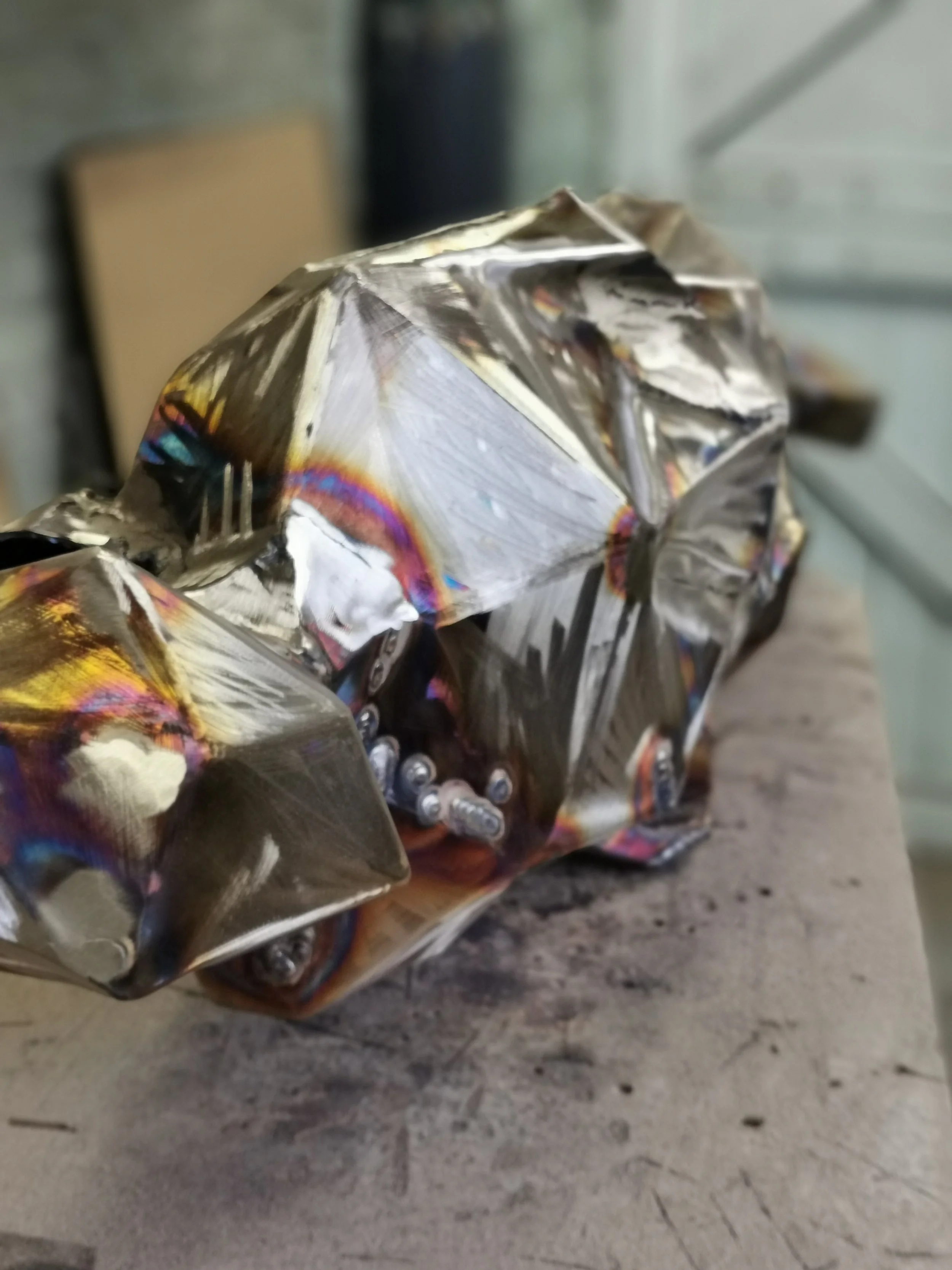 Close-up of a silver, crumpled, reflective cardboard box on a wooden surface.