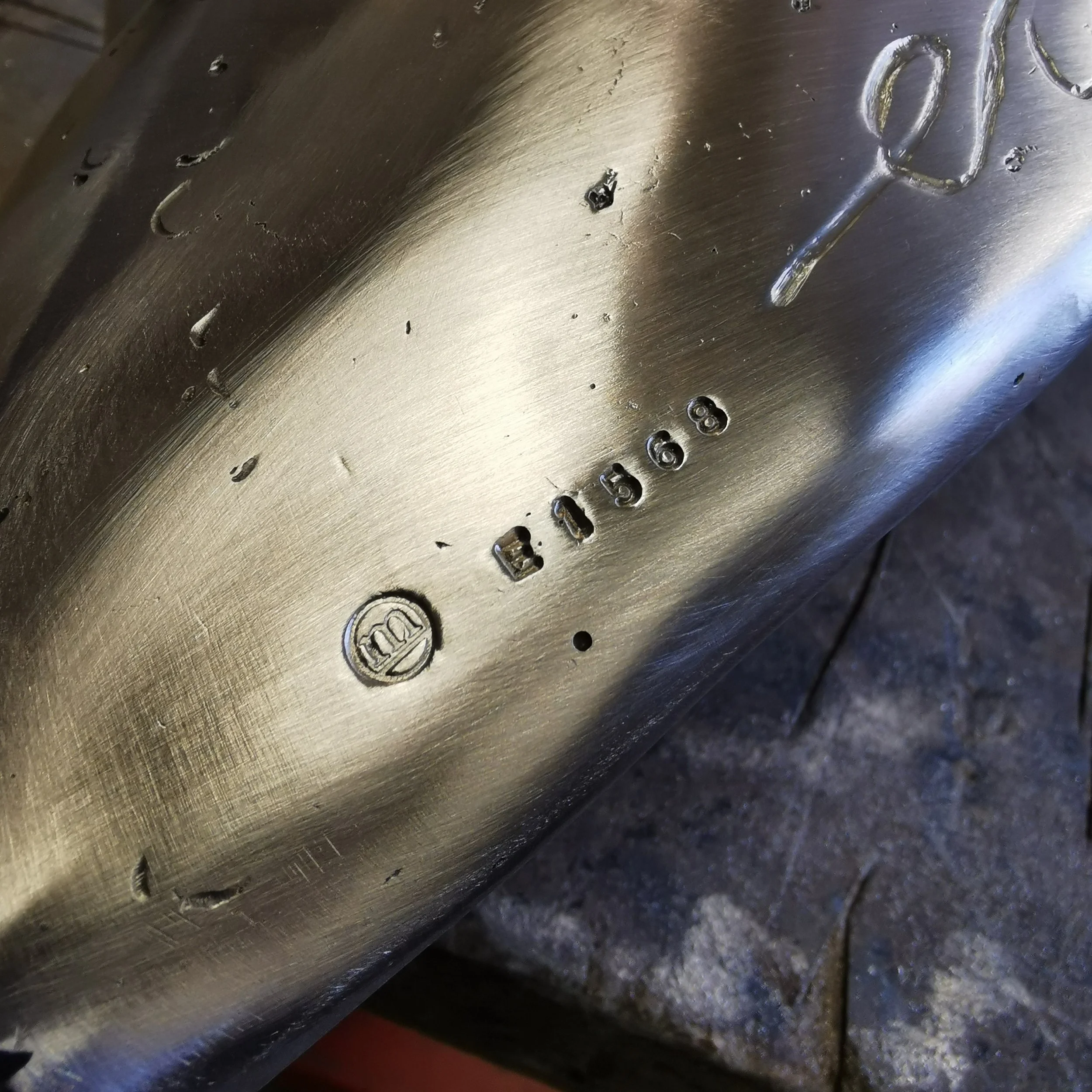 Close-up of a metallic surface with engraved numbers and symbols, showing scratches and small holes.