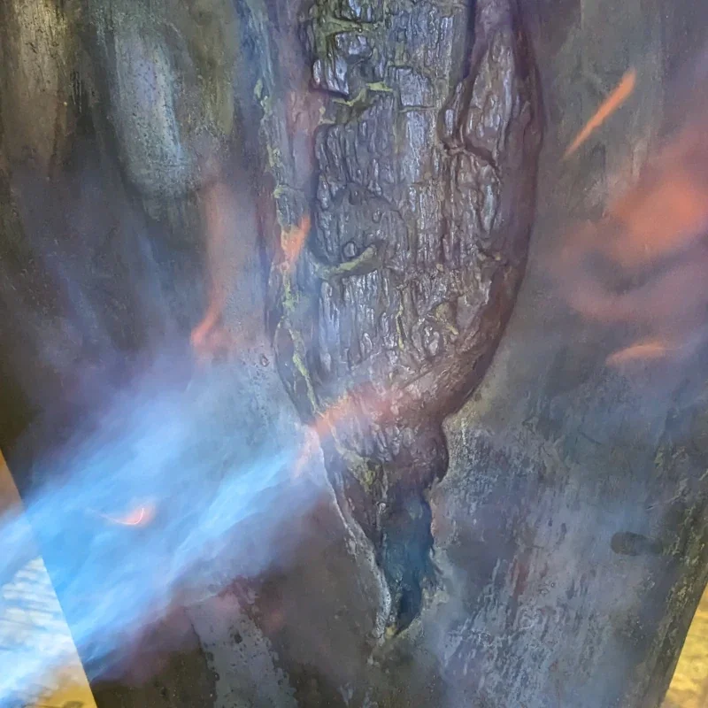 Close-up of a textured, weathered tree trunk with moss and cracks, with some orange and blue streaks of light reflecting on the surface.