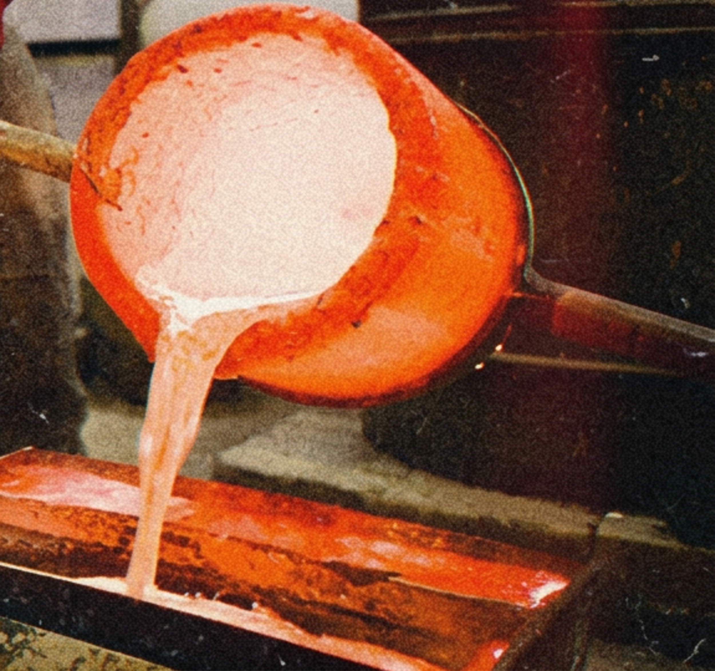 Close-up of a crucible with molten metal glowing orange inside, set against a dark background with sparks.