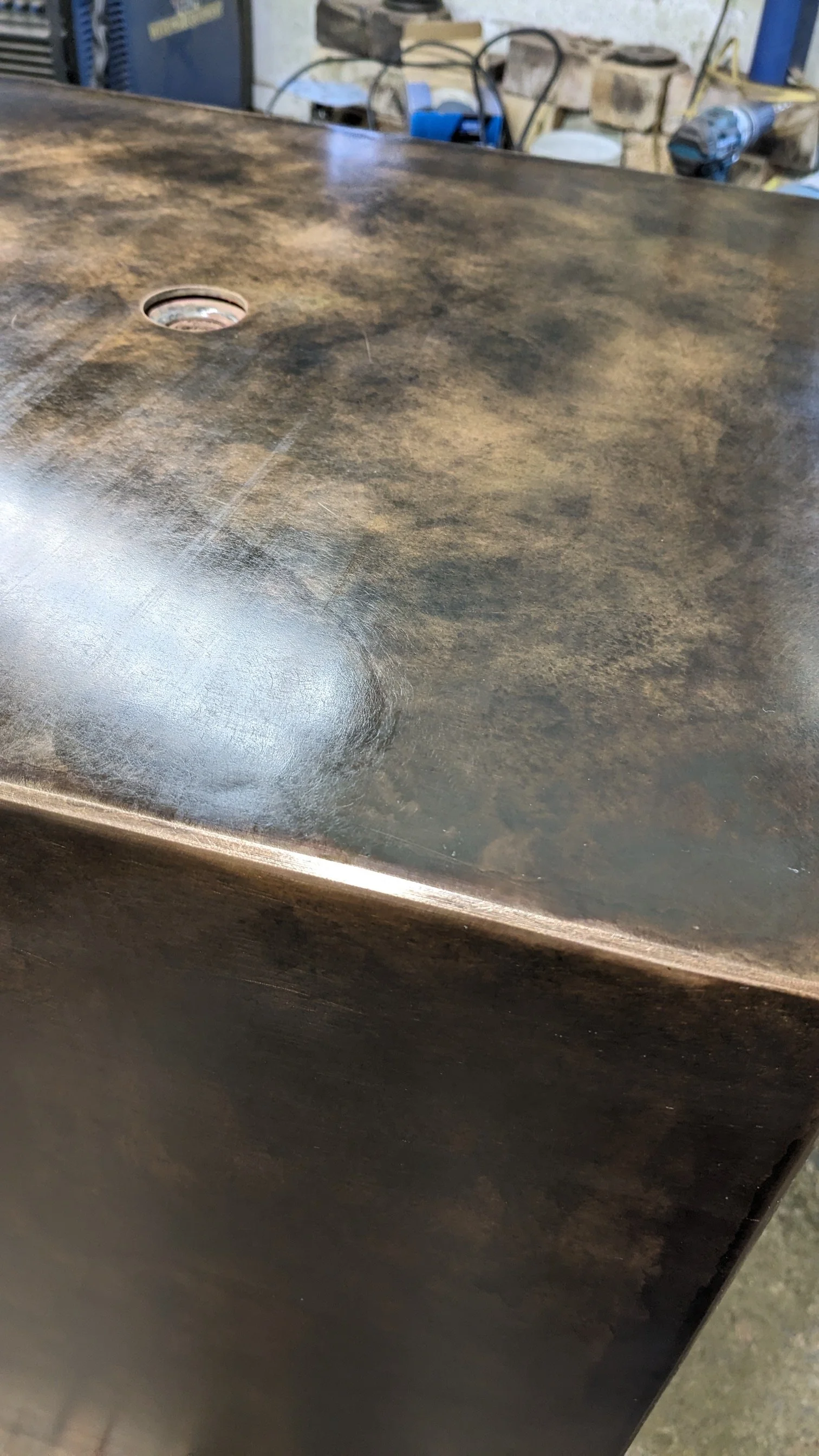 A close-up image of a dark, worn, and scratched metal surface with a circular hole.