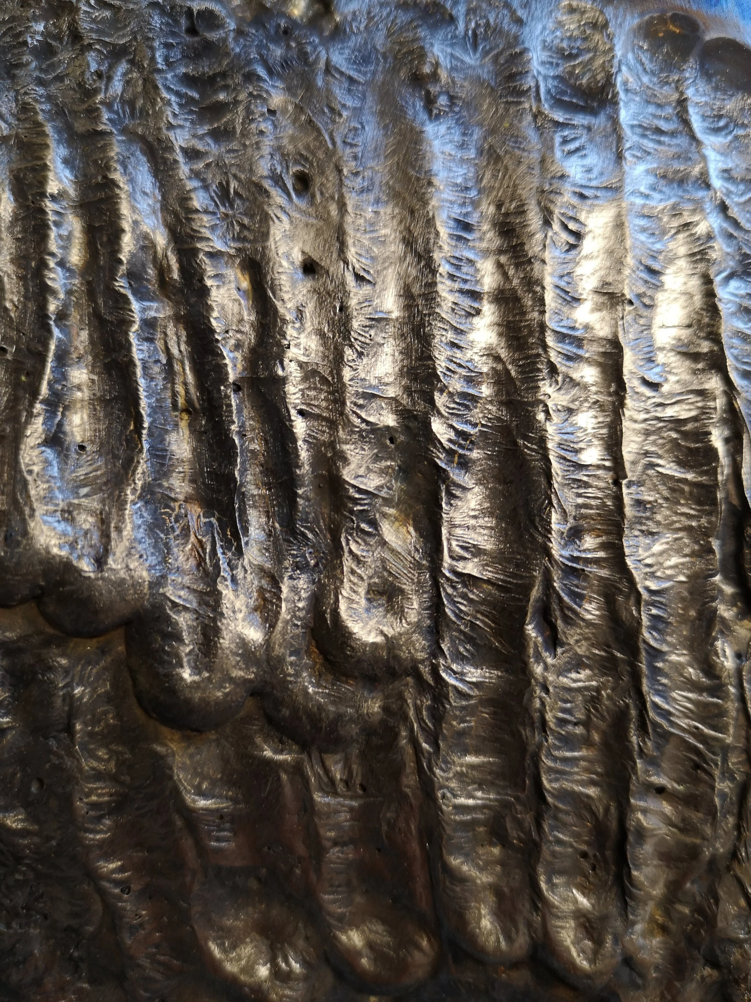 Close-up of a textured, metallic surface with ridges and crevices, possibly a sheet of crumpled or hammered metal.