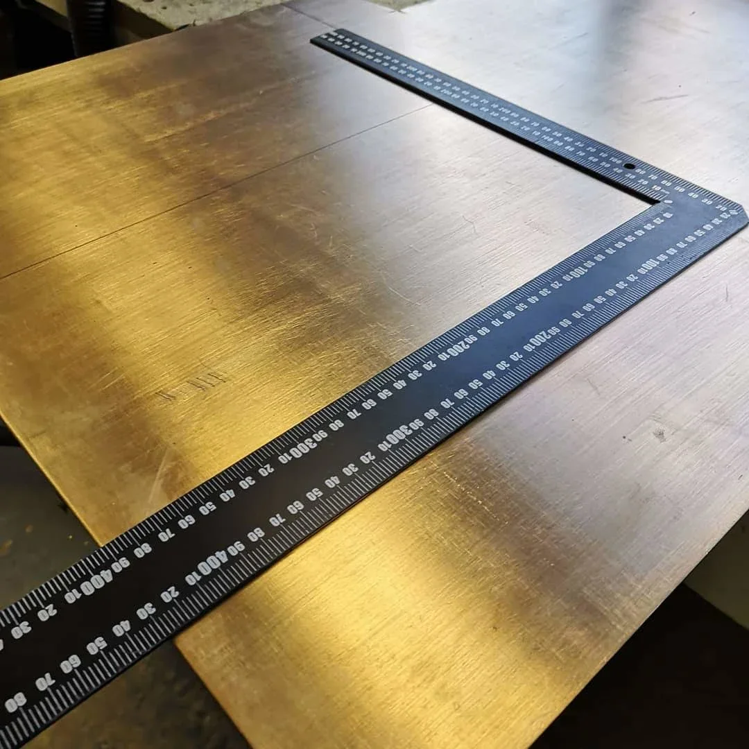 A metal square ruler on a wooden table.