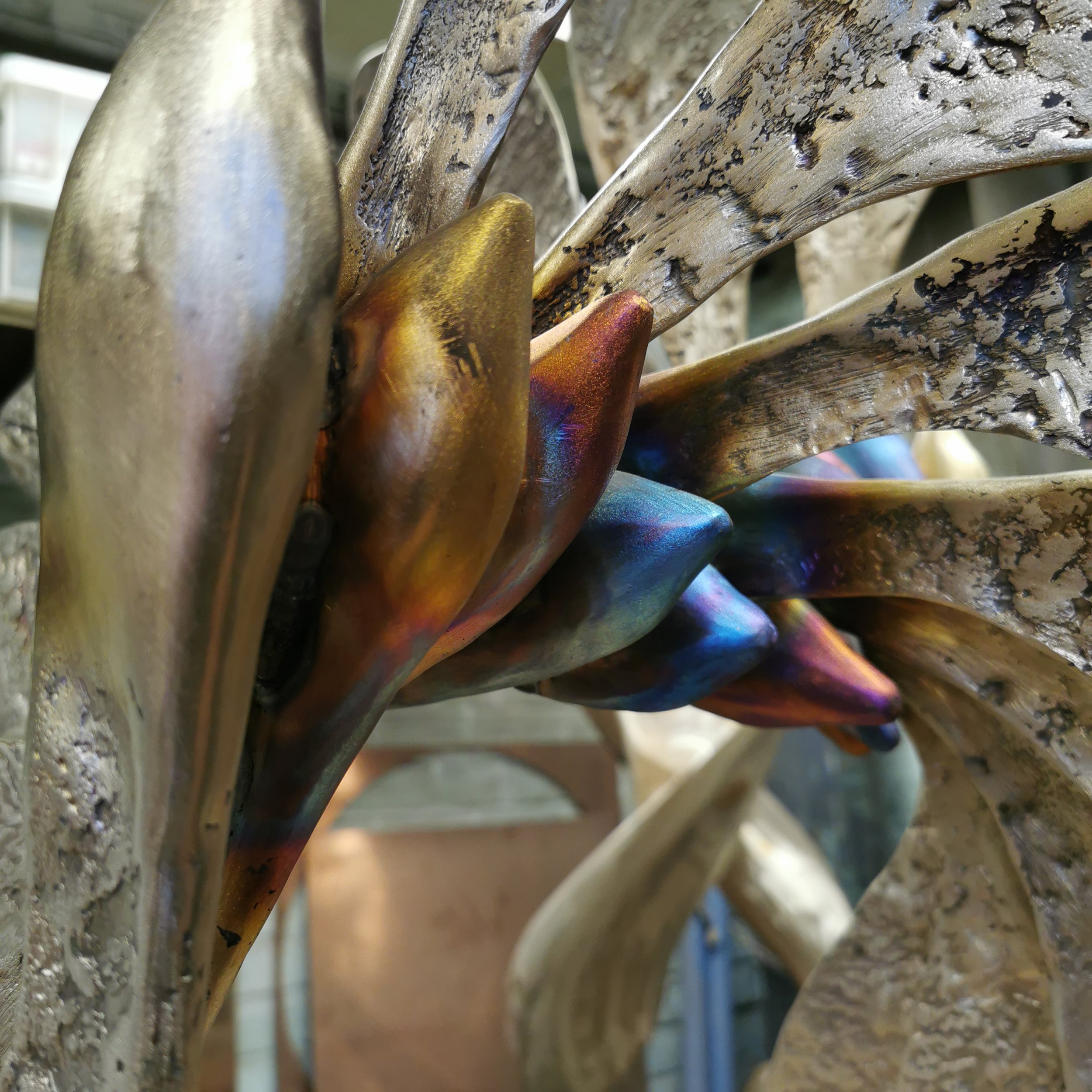 Close-up view of a pile of metallic objects with various colors, including gold, rainbow hues, and signs of corrosion or chipping, stored in a disorganized manner.