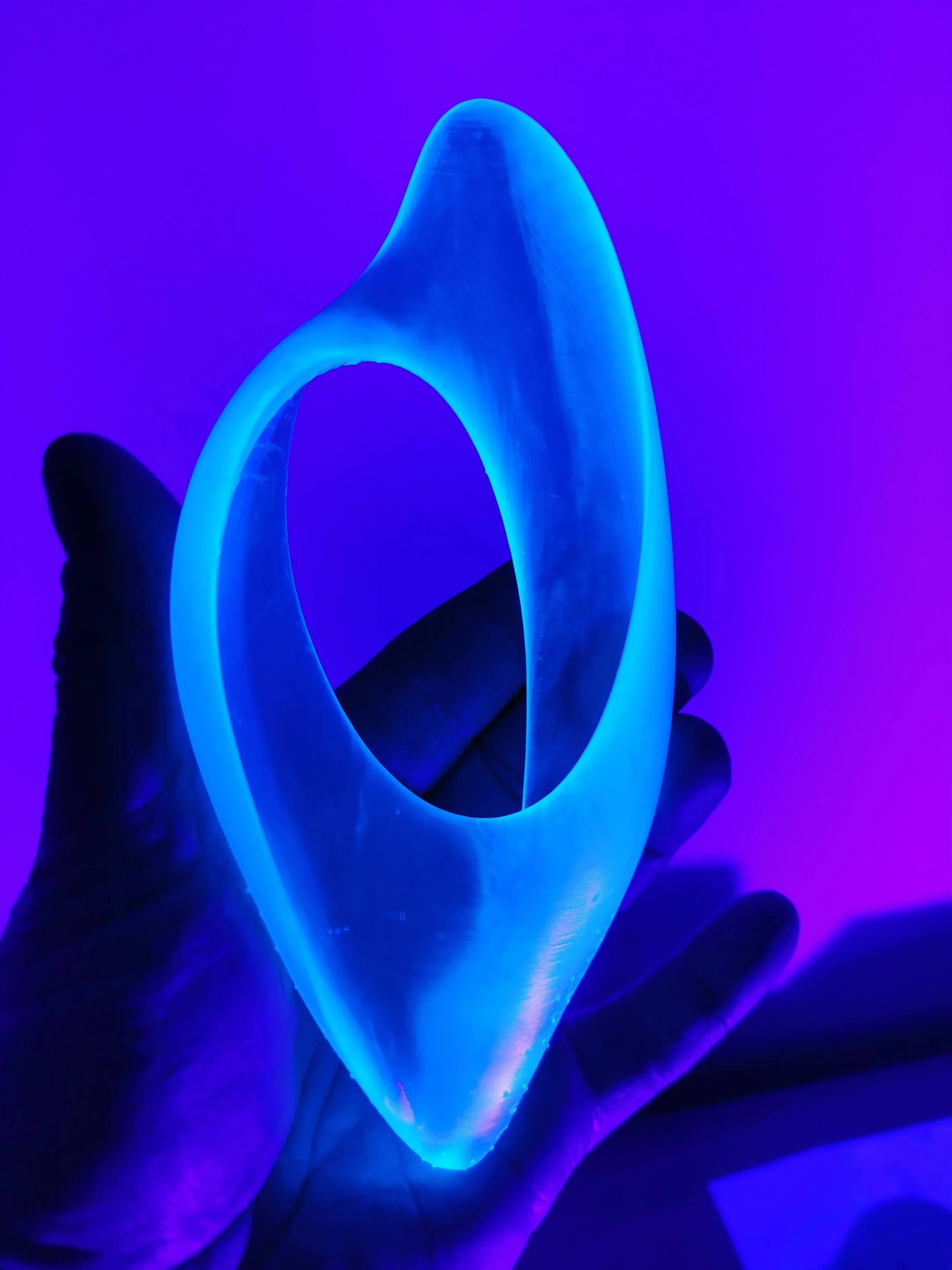A hand holding a glowing neon blue light tube against a purple background.