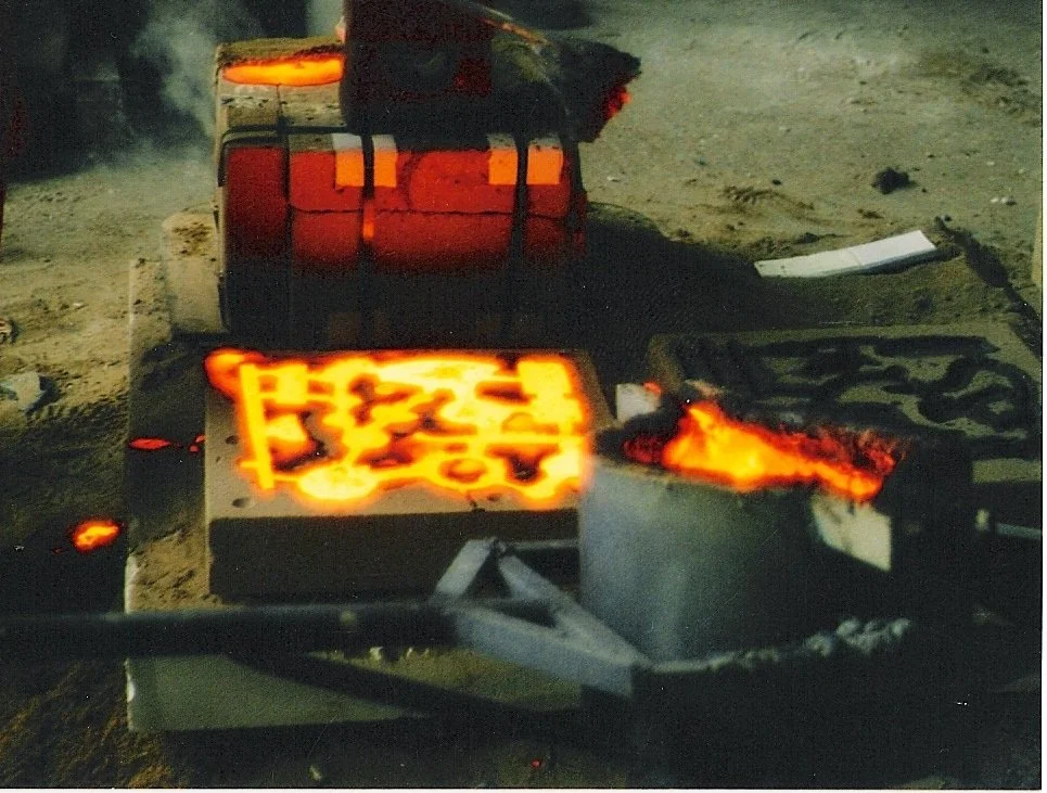 A foundry or metalworking process with molten metal being poured into molds at night.