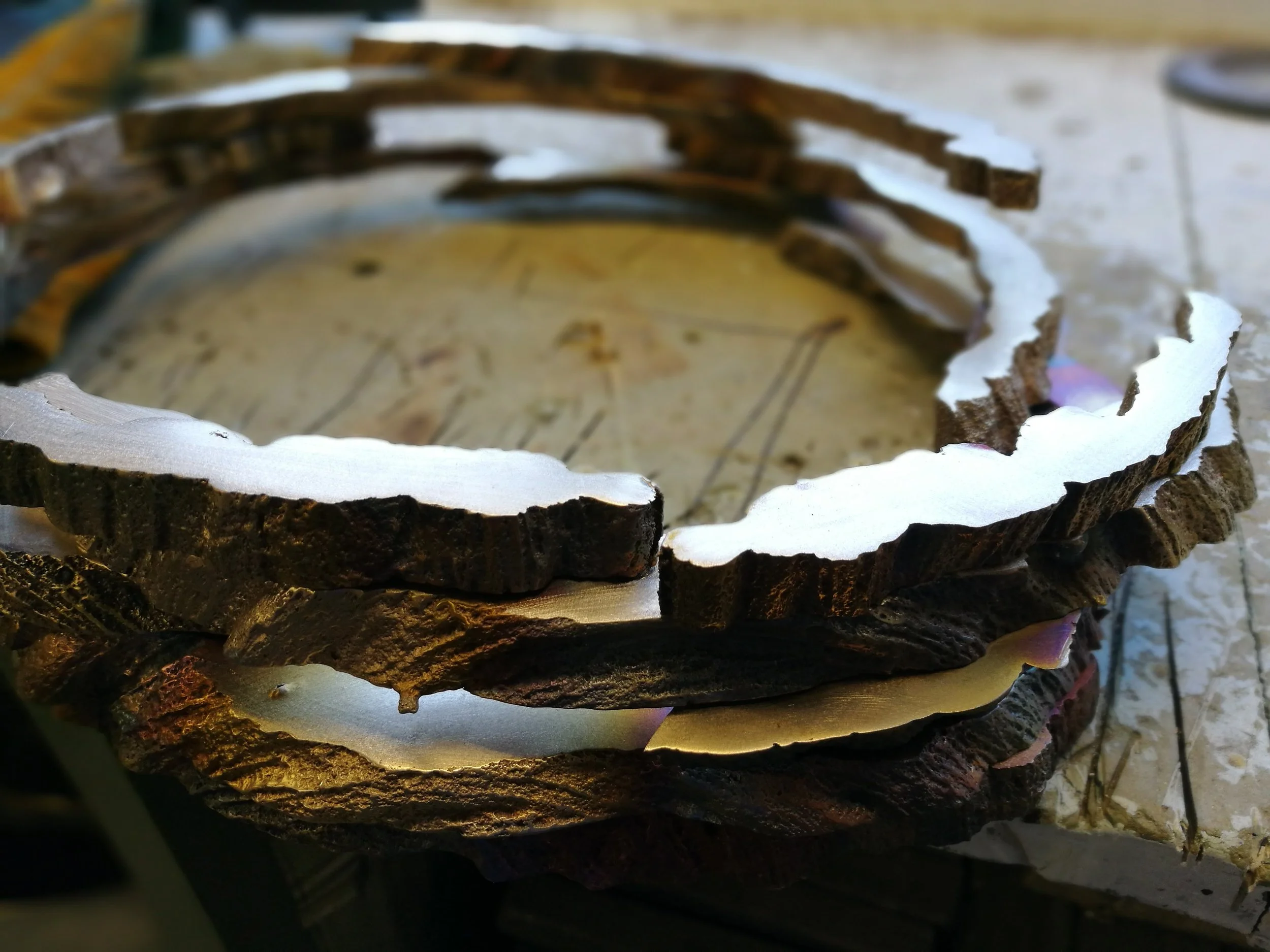 Close-up of a cake decorated to resemble a tree trunk, with textured brown frosting and white accents, placed on a table with a golden cloth.