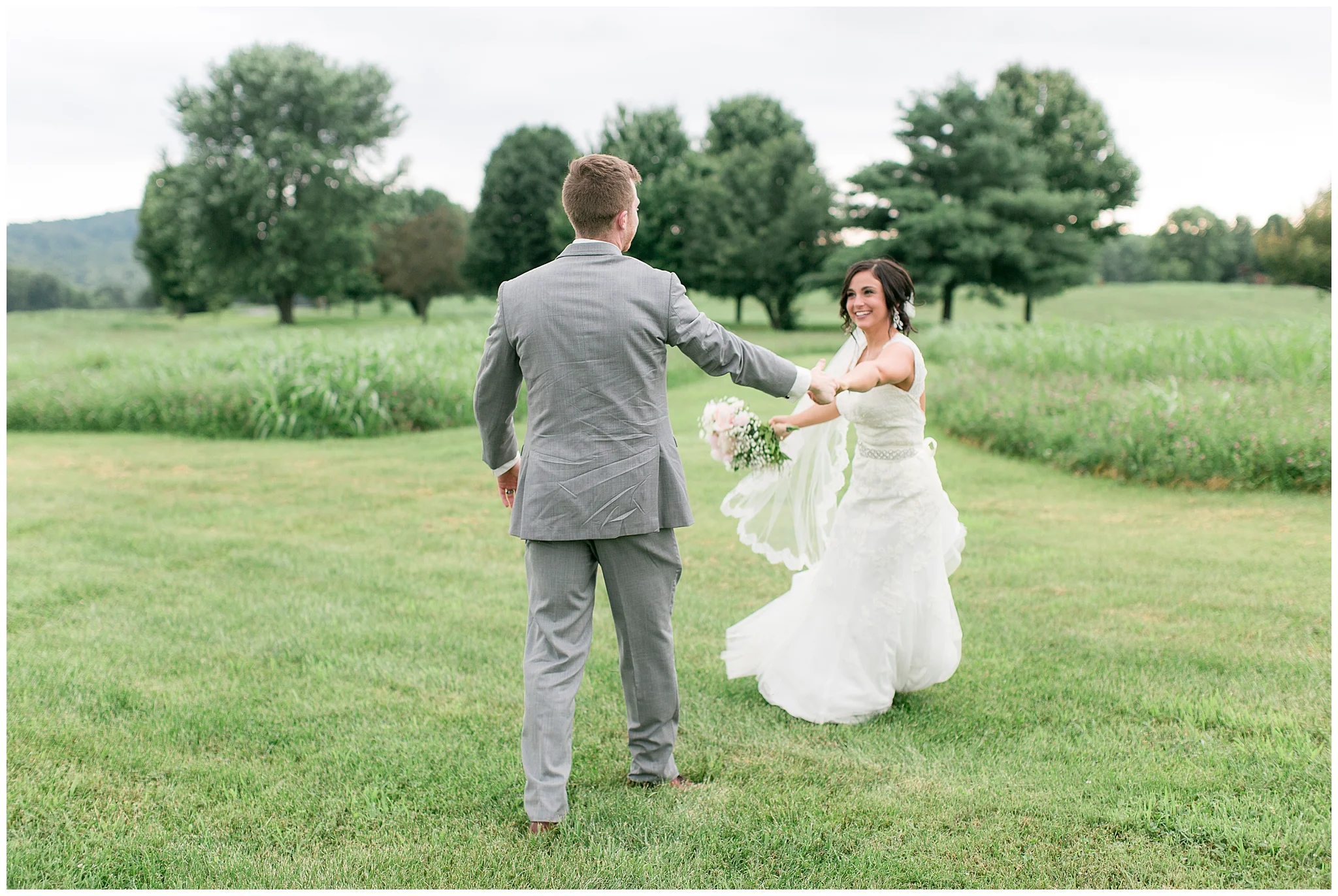 Danville Kentucky was the dreamy backdrop for Mackenzie and Bradley's July "I dos." This couple had months to plan their perfect day, but the venue change the day before threw them for a loop! Nobody could have pulled in off as flawlessly as this perfect couple and their awesome bridal crew! It's all in the details with this unique barn wedding. The ceremony arch was wrapped with white silk, eucalyptus, and beautiful flowers waiting for the even more stunning bride. Mackenzie wore a lace dress with a sweetheart neckline from David's Bridal and had a custom-made veil pinned in her curls. The bridesmaids (yes, there were a lot!) wore shades of green to compliment the grey suits worn by the groomsmen. Bradley's reaction to Mackenzie walking down the aisle was so precious; all the family members were tearing up! The night was spent capturing every single sweet moment between the two of them. They made sure to include tons of time for dancing so the floor was filled with laughing and fun until the final send off. As everyone blew bubbles in the happy couples way, they drove off and started their lives together.