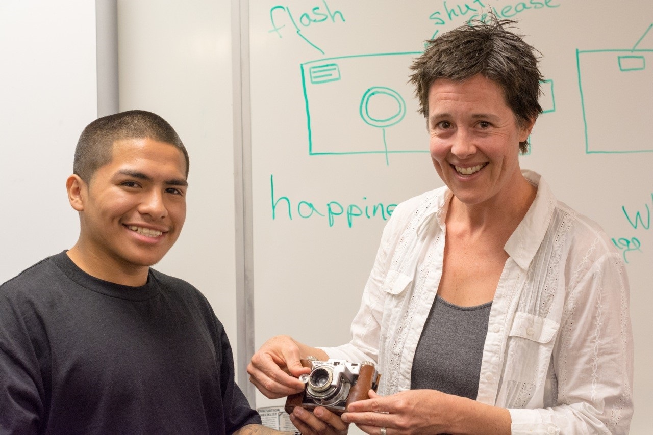 A teacher and student holding a camera together during our Arts Component focused on photography.