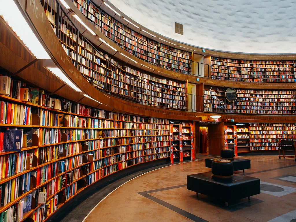 An image of a library. Hundreds of books on bookshelves appear in the image. Photo credit: square(tea) on flickr