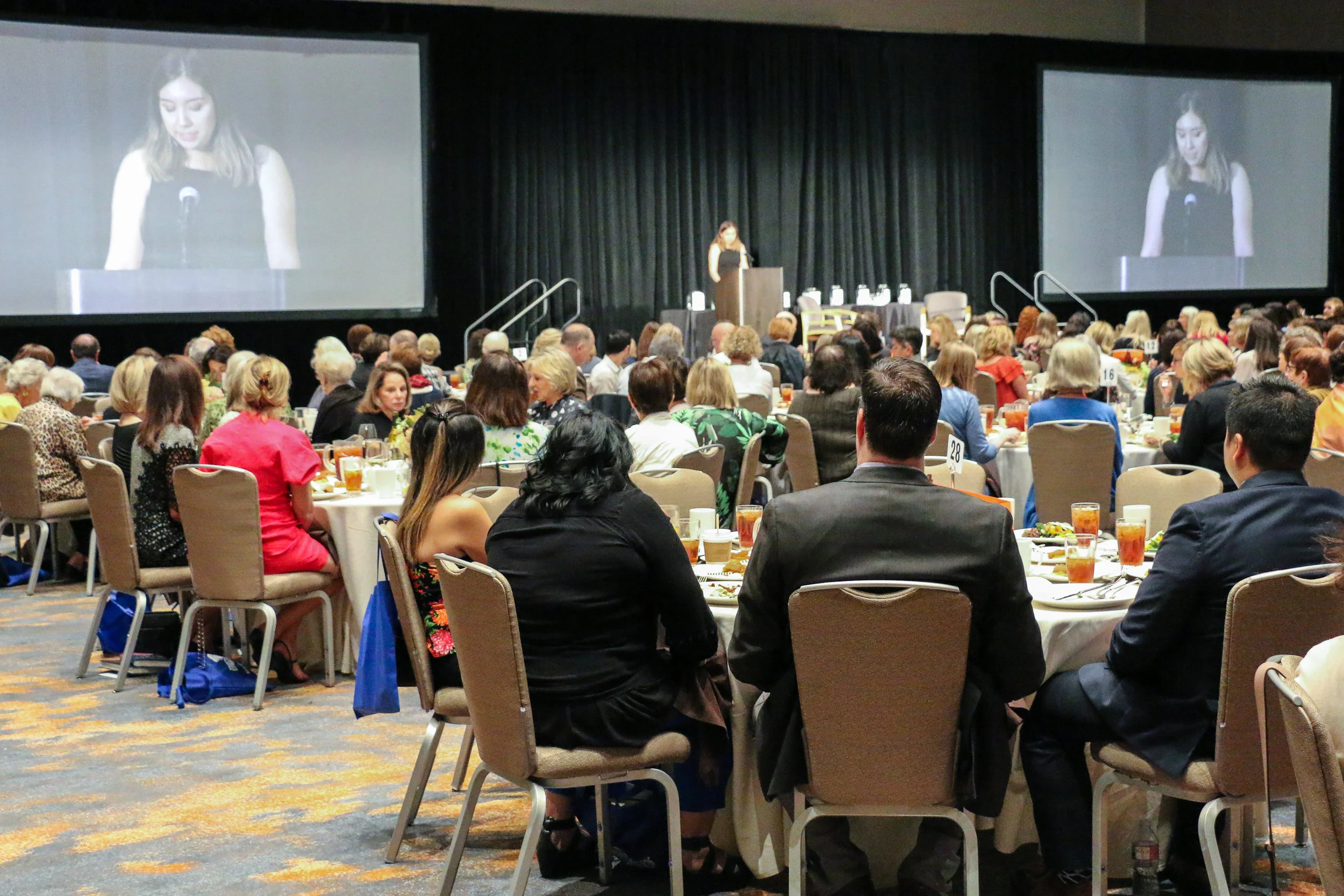 An image of our audience at the 15th Annual Author’s Luncheon & Fundraiser watching Brittany Jackson, former ABG and WAWS participant, give her speech.