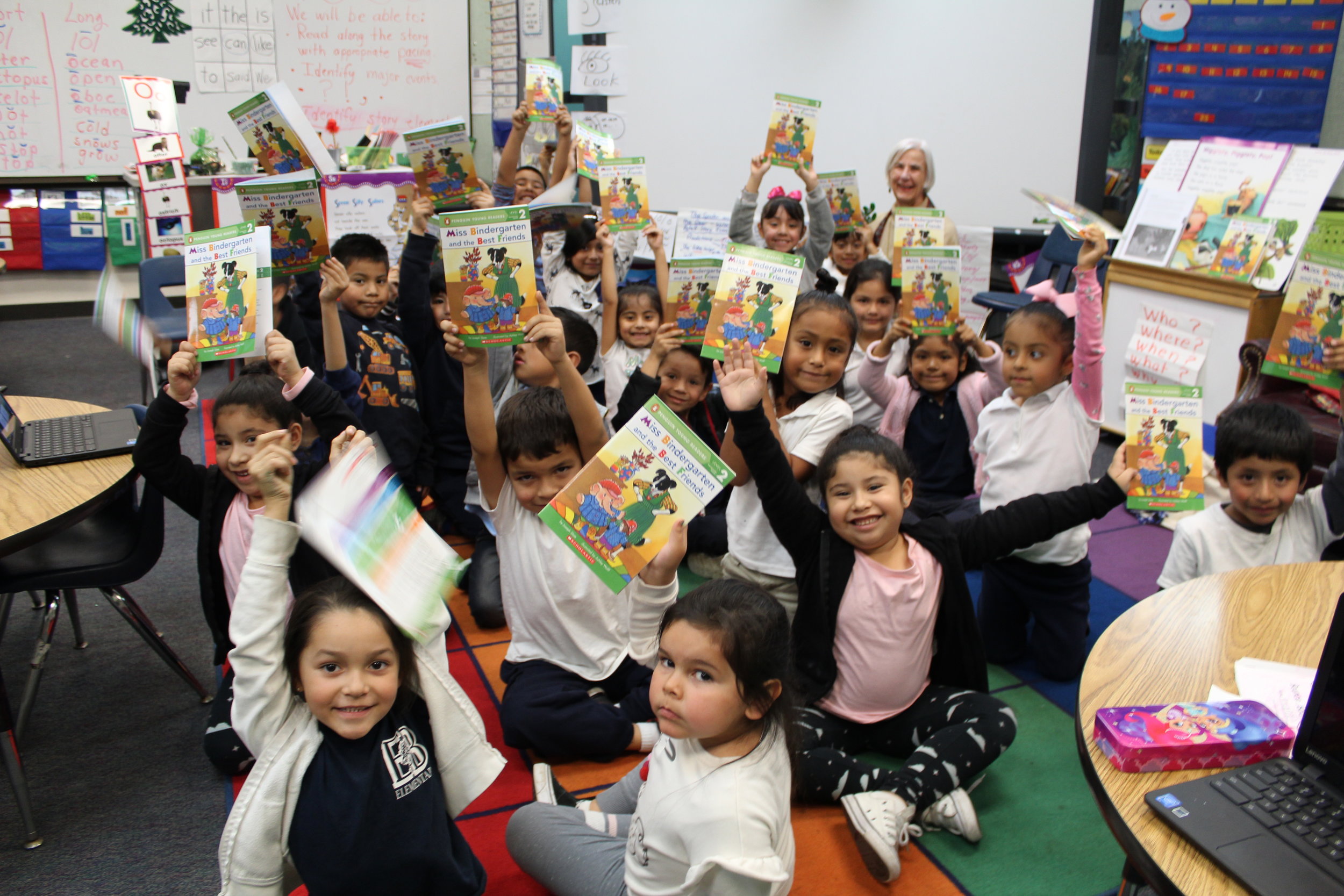 An image of a group of students in our Read Aloud Program excitedly holding up their books.