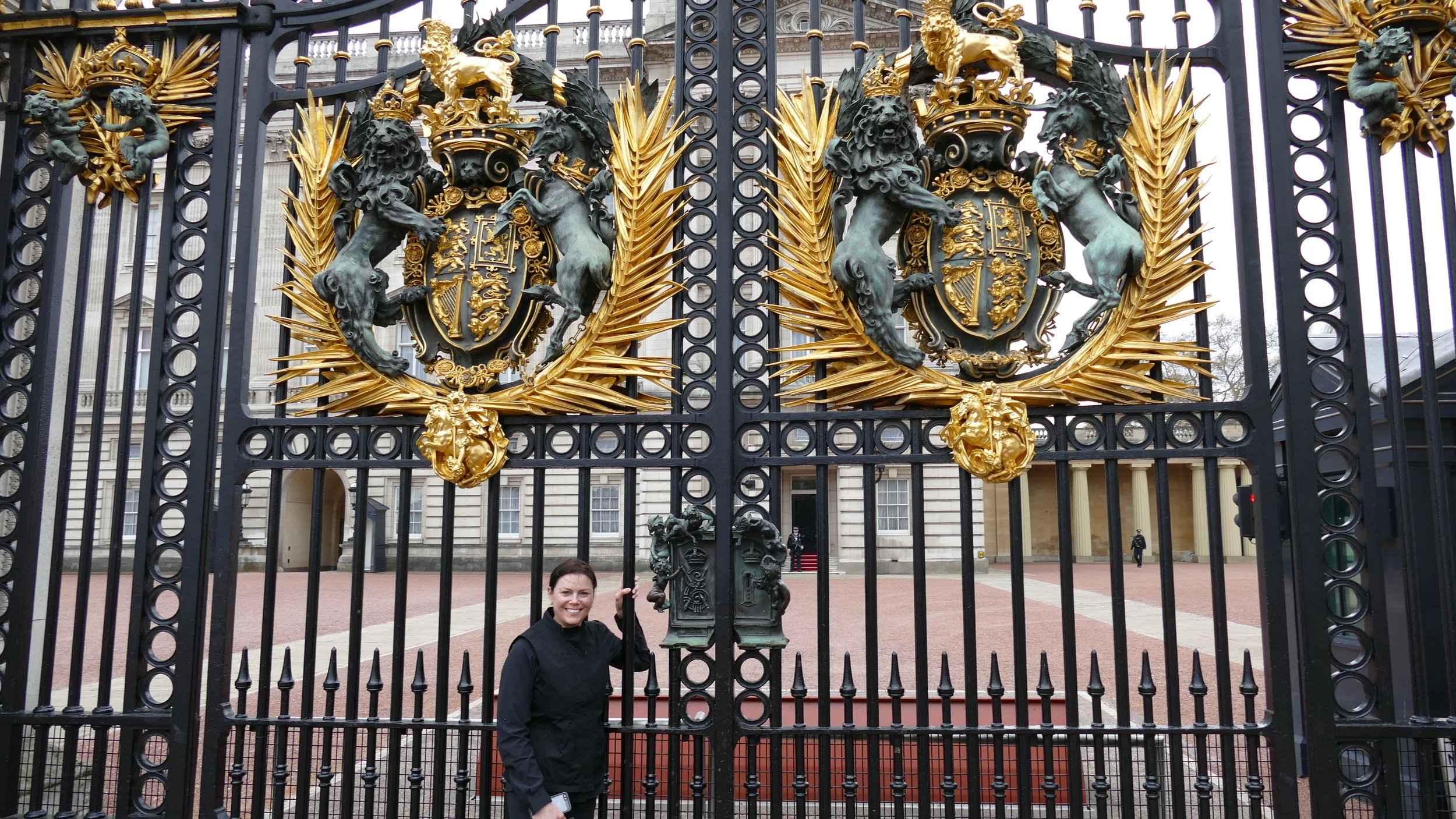 Alecia (in the rain) at the gate of Buckingham Palace