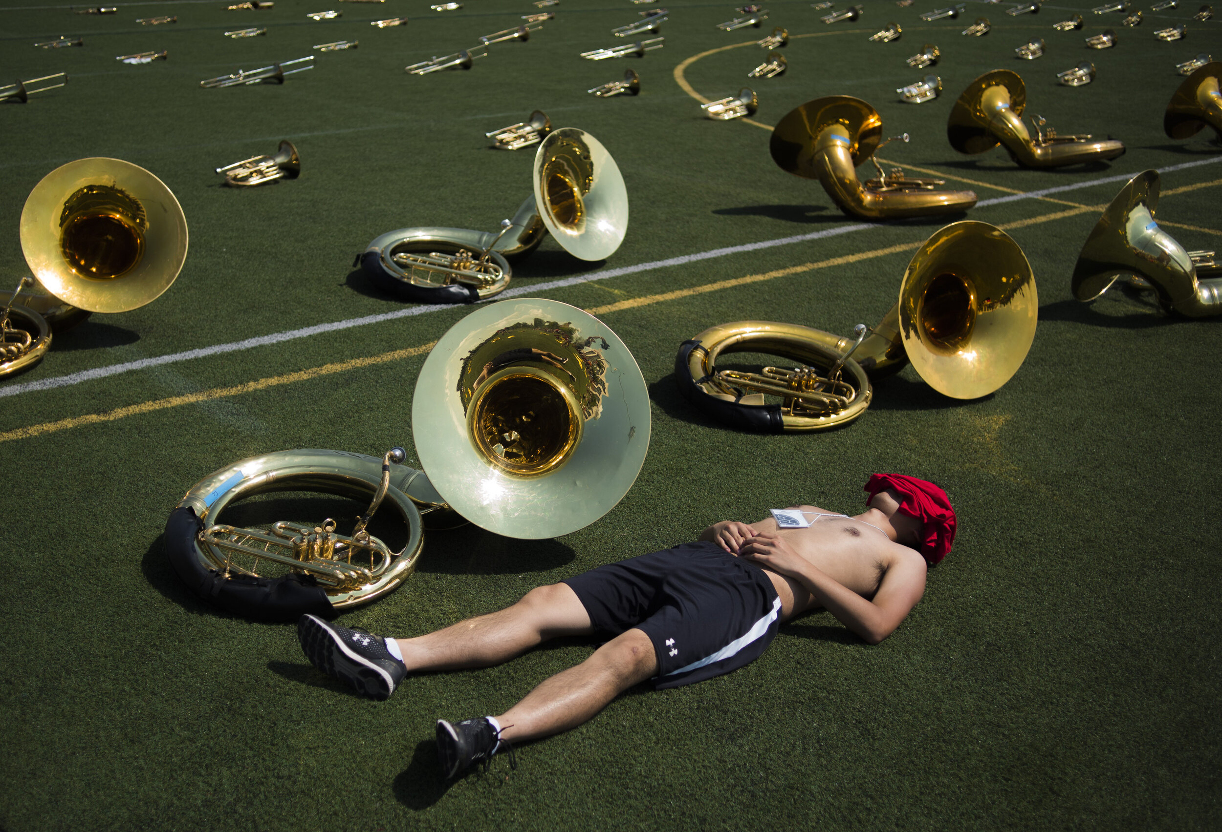  James Shen, a tuba player for the University of Maryland's marching band, spends his water break napping on the astroturf during the first week of rehearsals back after summer break on Tuesday, August 20, 2019.  