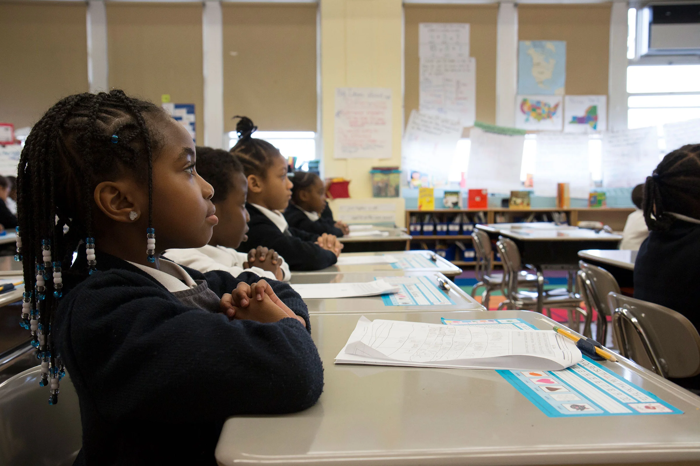 First grader, Nylah, folds her hands while she waits for class instruction.