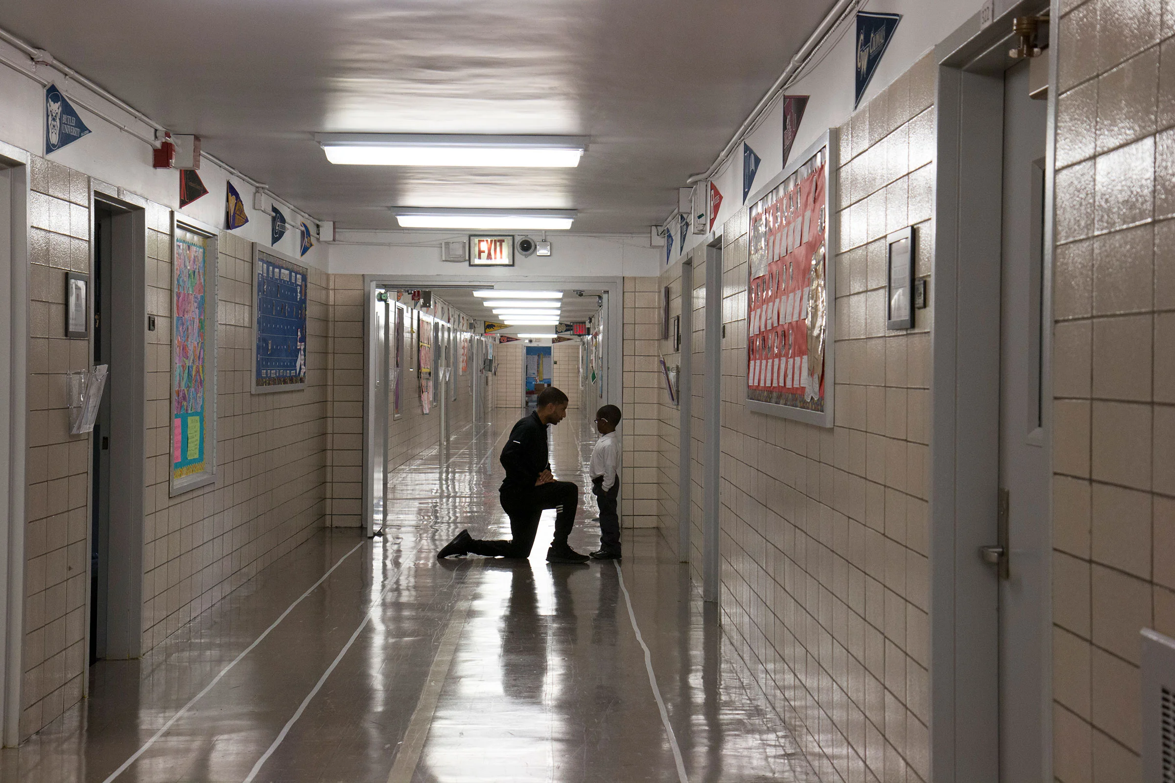 Gibran Jordain-Earl, a fitness teacher and coordinator of the community involvement program at Leadership Prep Canarsie, talks to a student in the hall.