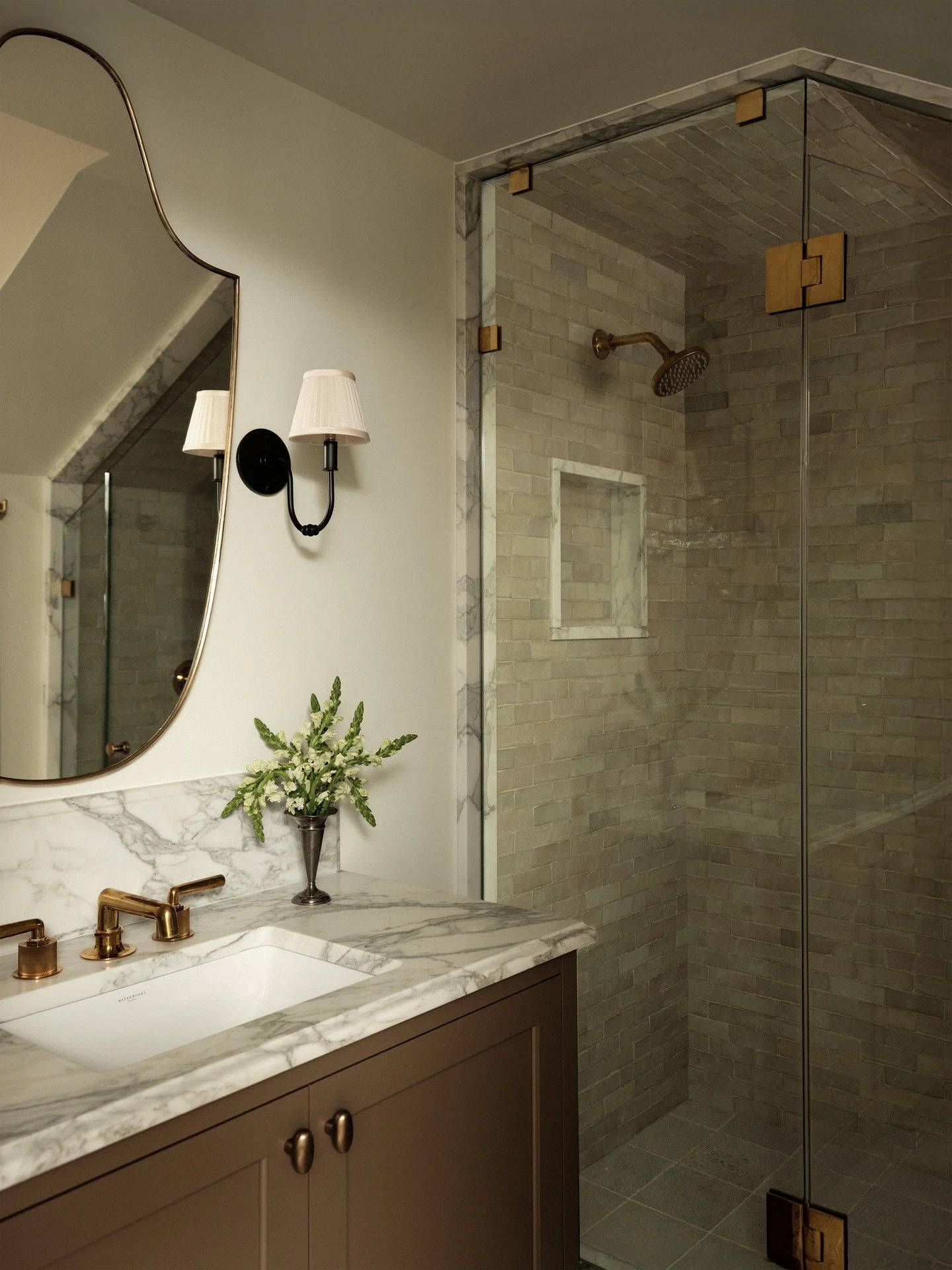 From concept to completion, this petite windowless ensuite was designed to feel anything but closed in. Earthy tones, refined silhouettes, vintage pieces, mixed metals, and an intentional blend of zellige and limestone layer together to bring an unma