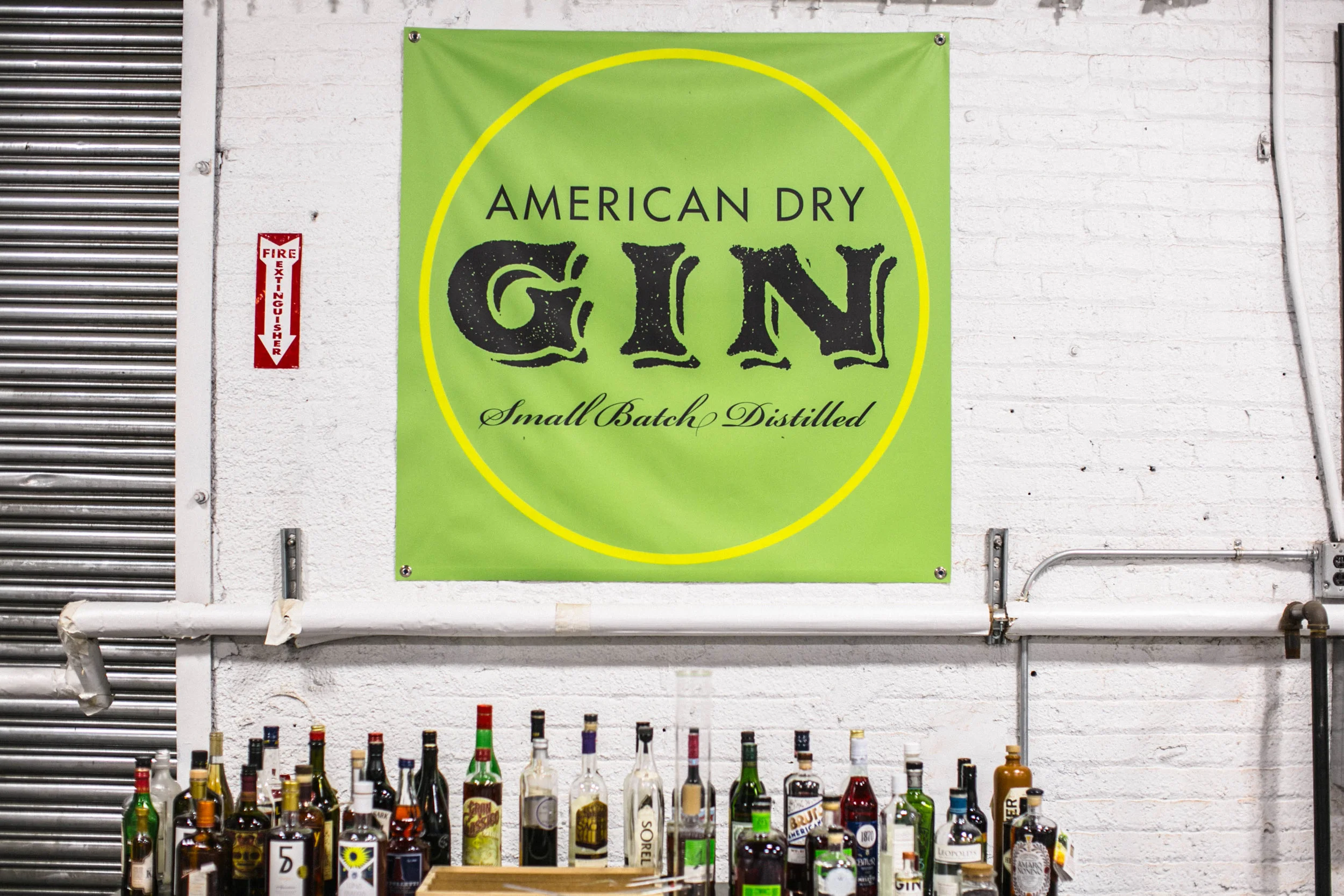 Signature bottles stand beneath the Greenhook Gin flag in the modest Greenpoint distillery.