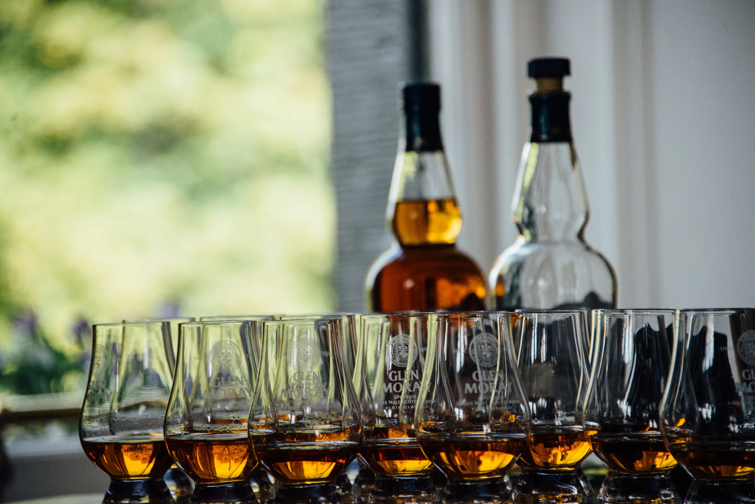 Above: From Glen Moray's bottle archives, a vintage single malt bottled in the 1970s sits atop ledgers that serve as a working history of the distillery. Below: Drams of Glen Moray's current single malt expressions.