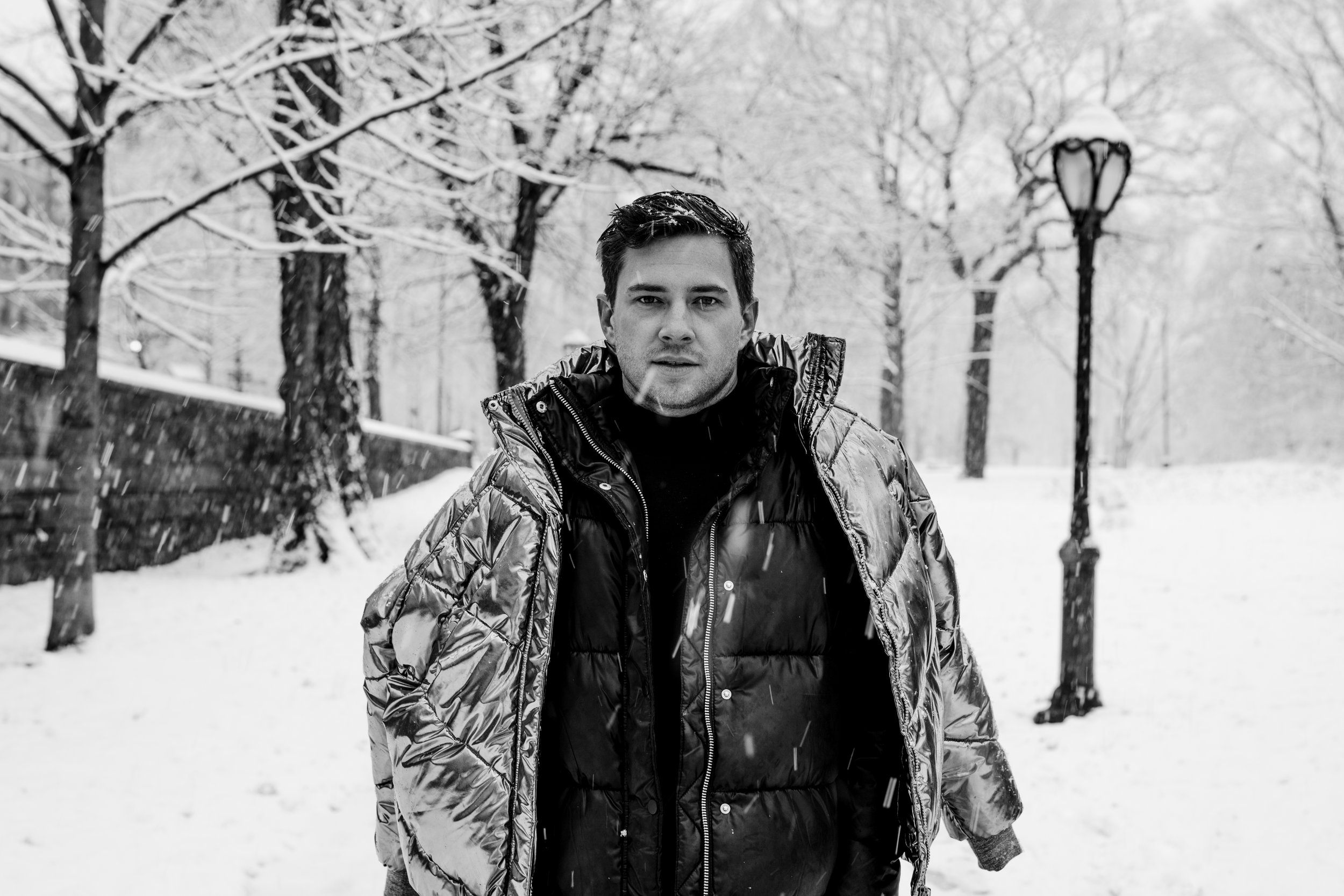 Black and white photo of man in snowy park wearing puffer coats