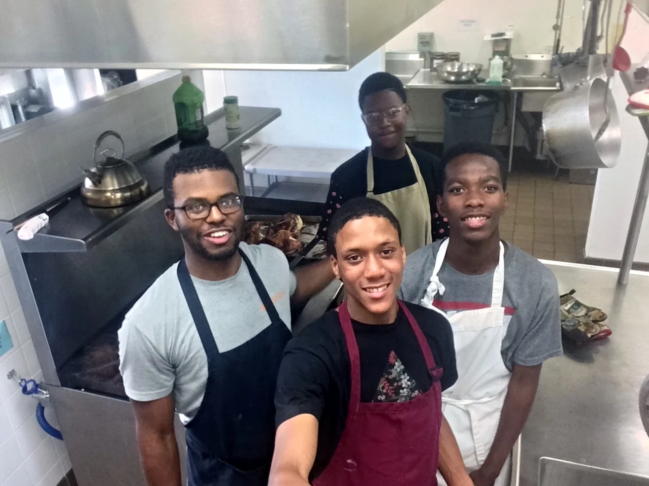 Milton (left) with Dj (center Background) and other members of Urban Hope's Young Leaders Group cooking dinner before our biweekly meeting.