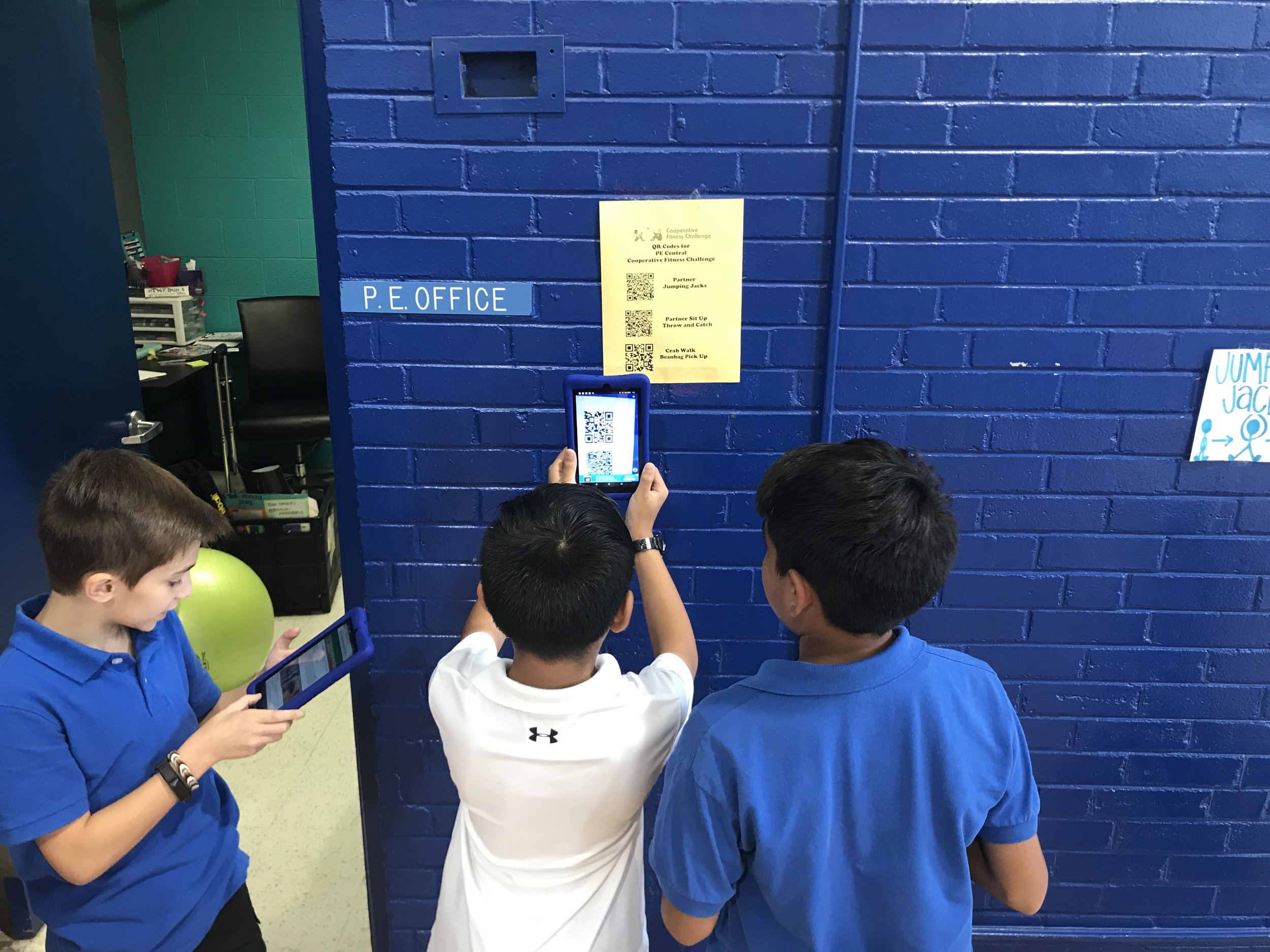  These students are using their kindles in the gym to find out what activity is next in their fitness challenge. 