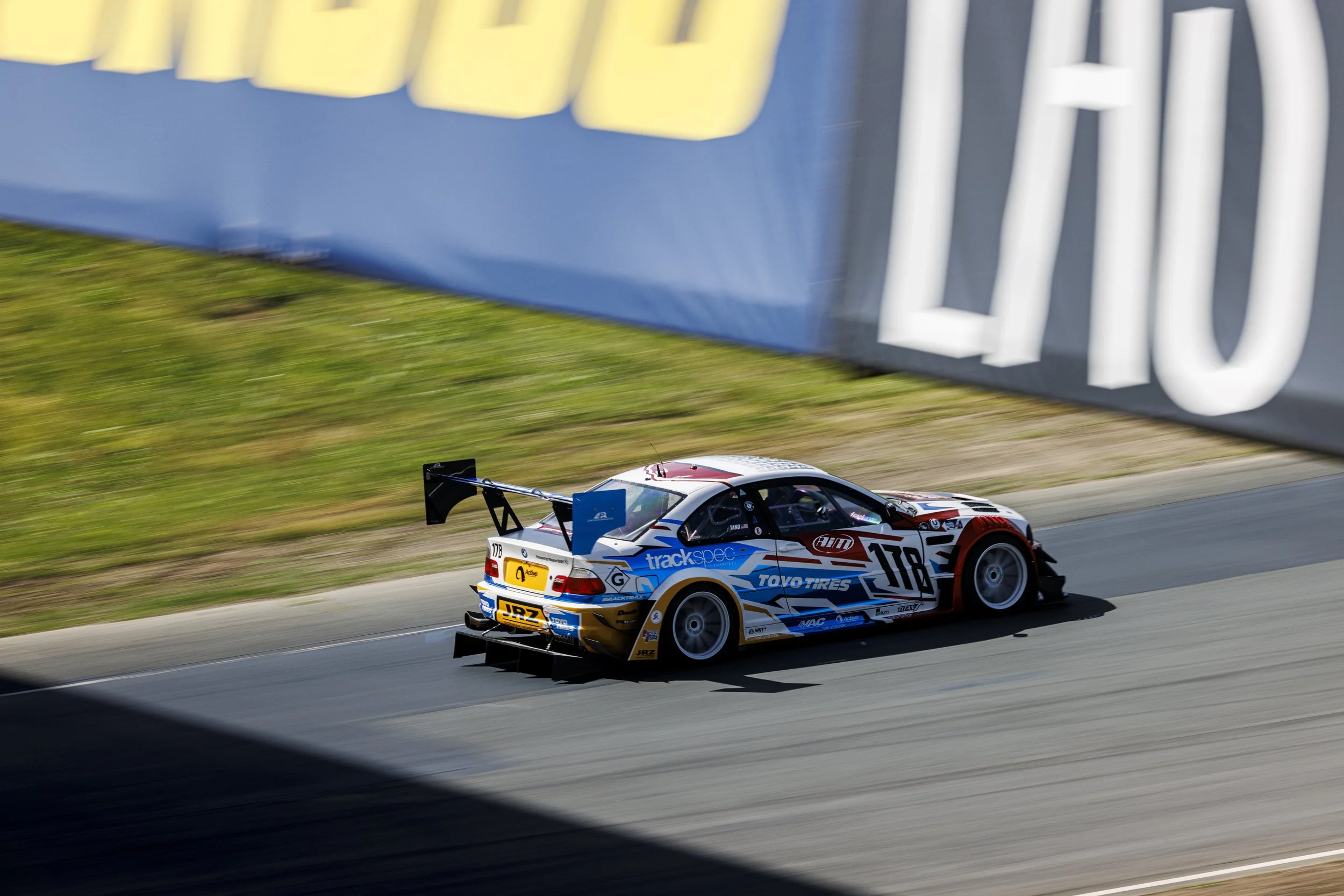 Race car on track with blue and white advertising banners overhead