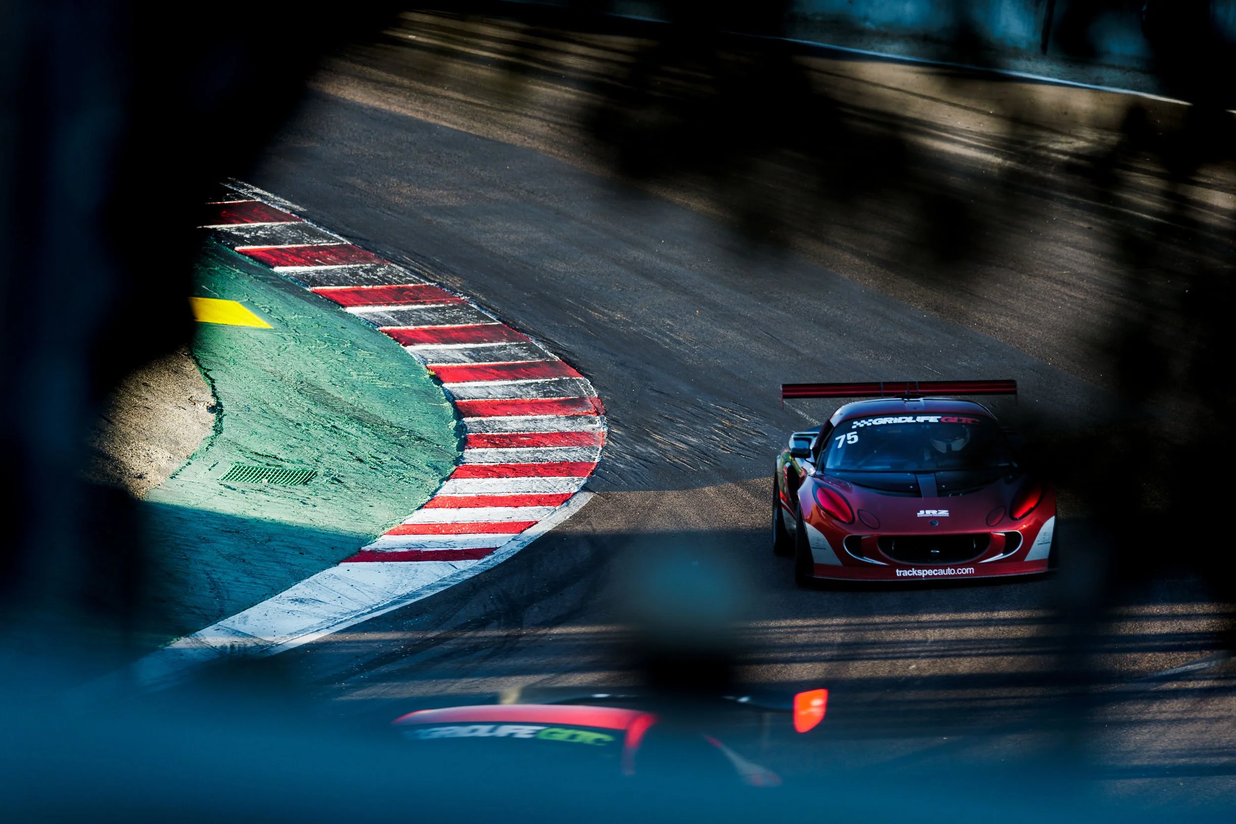 A red race car with a spoiler on a racing track during daytime.