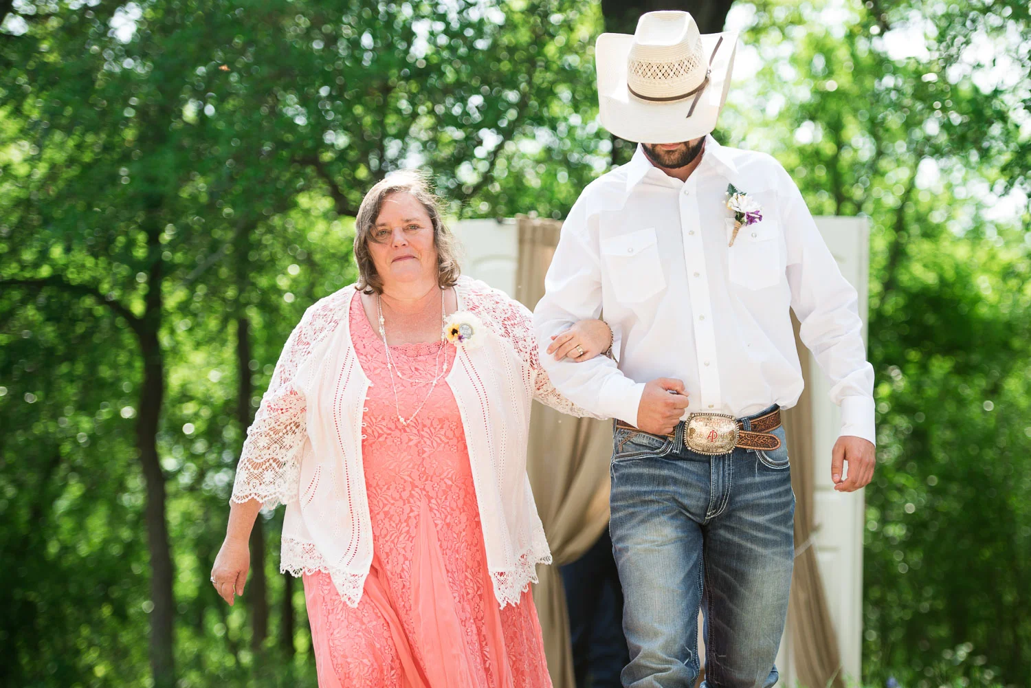 26 Mother of the bride is ushered down the aisle by the groomsman in a cowboy hat.jpg