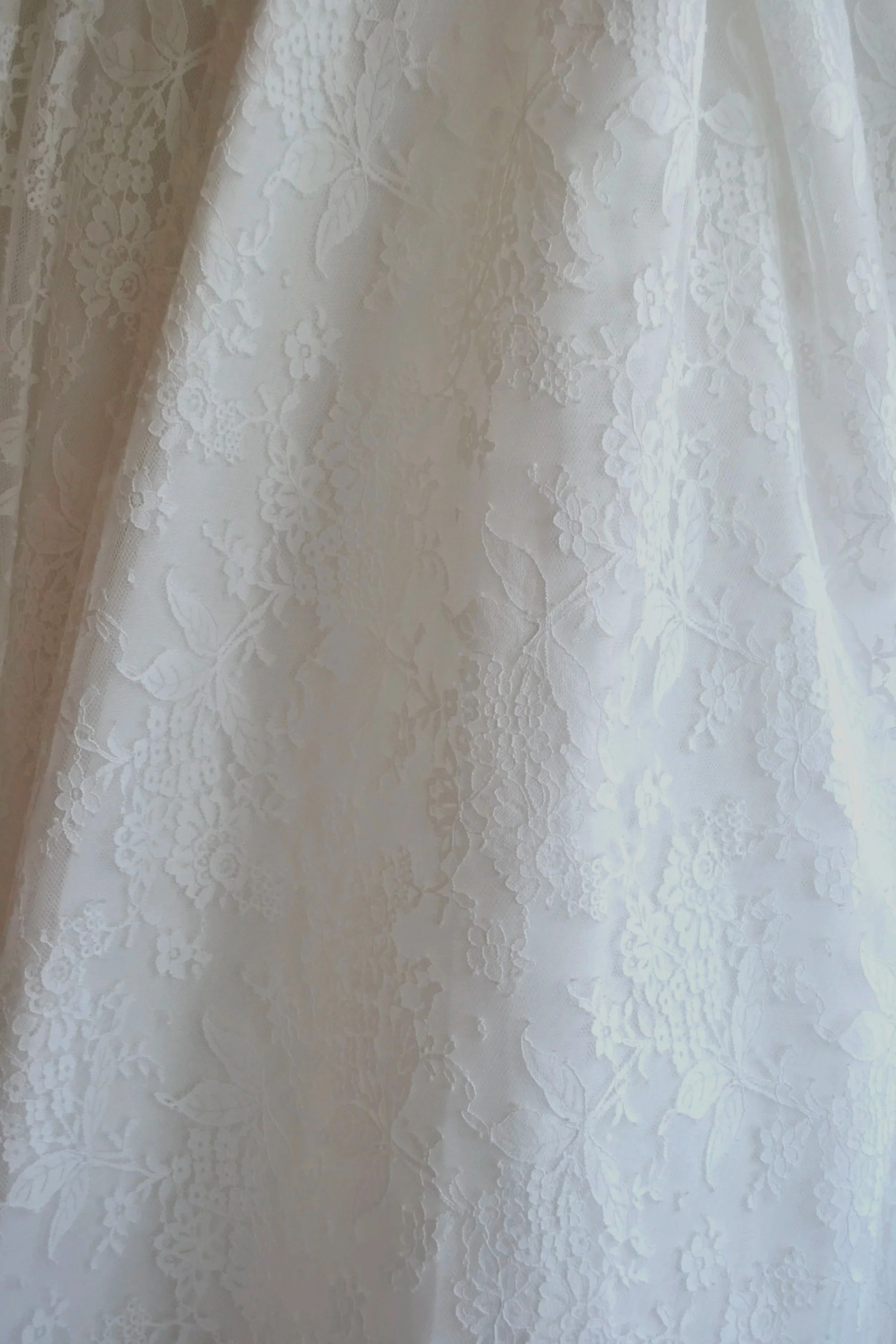Close-up of white lace fabric with floral pattern.