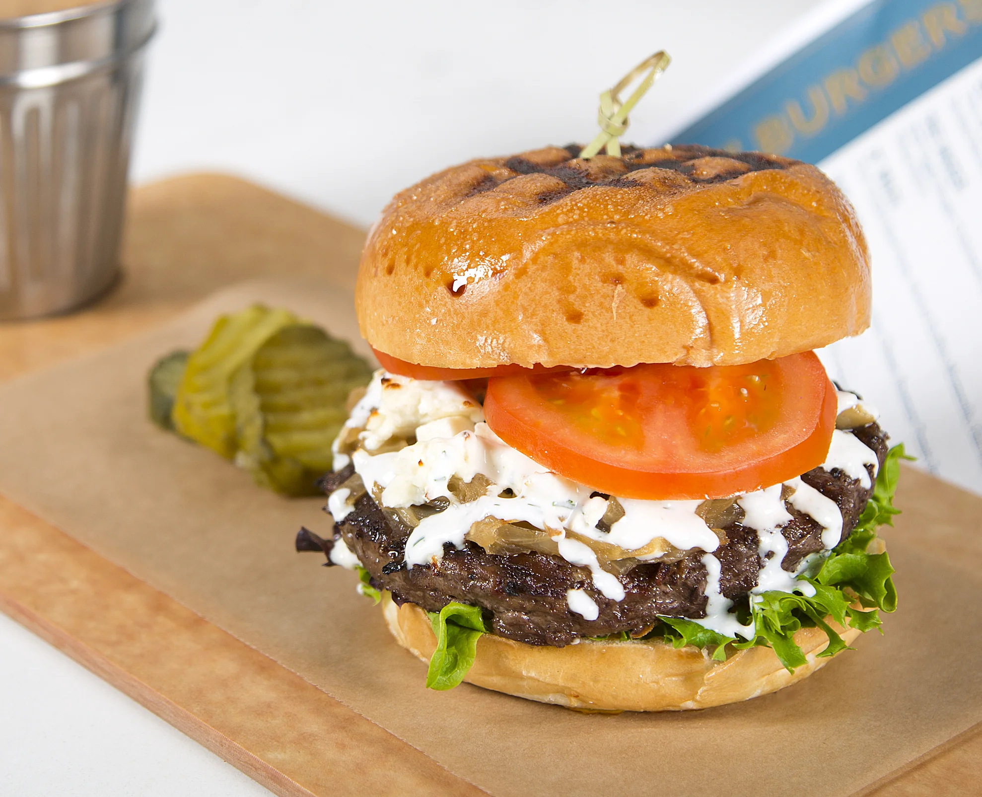 LITTLE BO PEEP Spiced Artisan Lamb Burger, Caramelized Onions, Aged Feta Cheese, Field Greens, Florida Tomato, Tzatziki Sauce, Pita Round