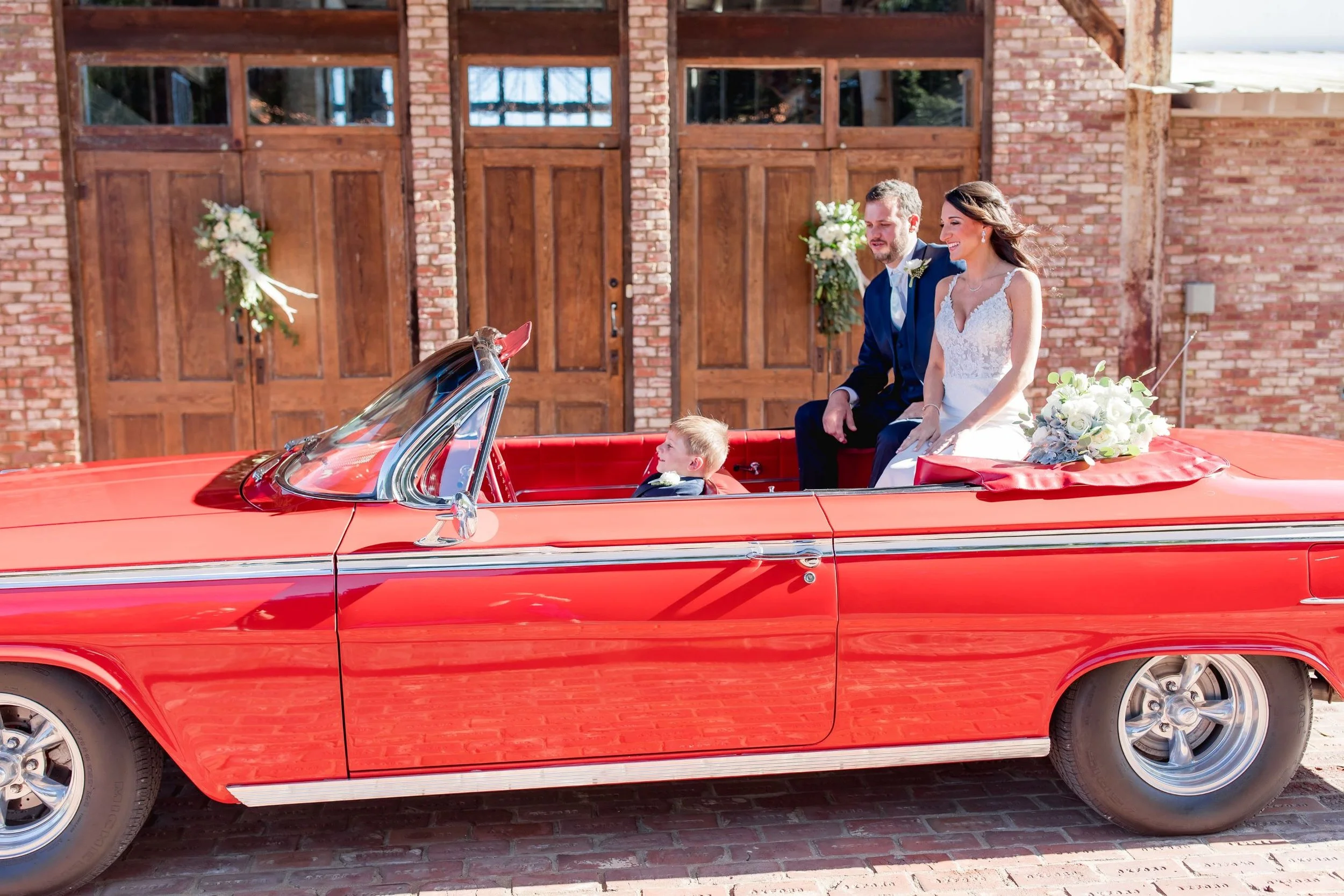 couple in red convertible at front of venue on wedding day at jefferson oxford ms