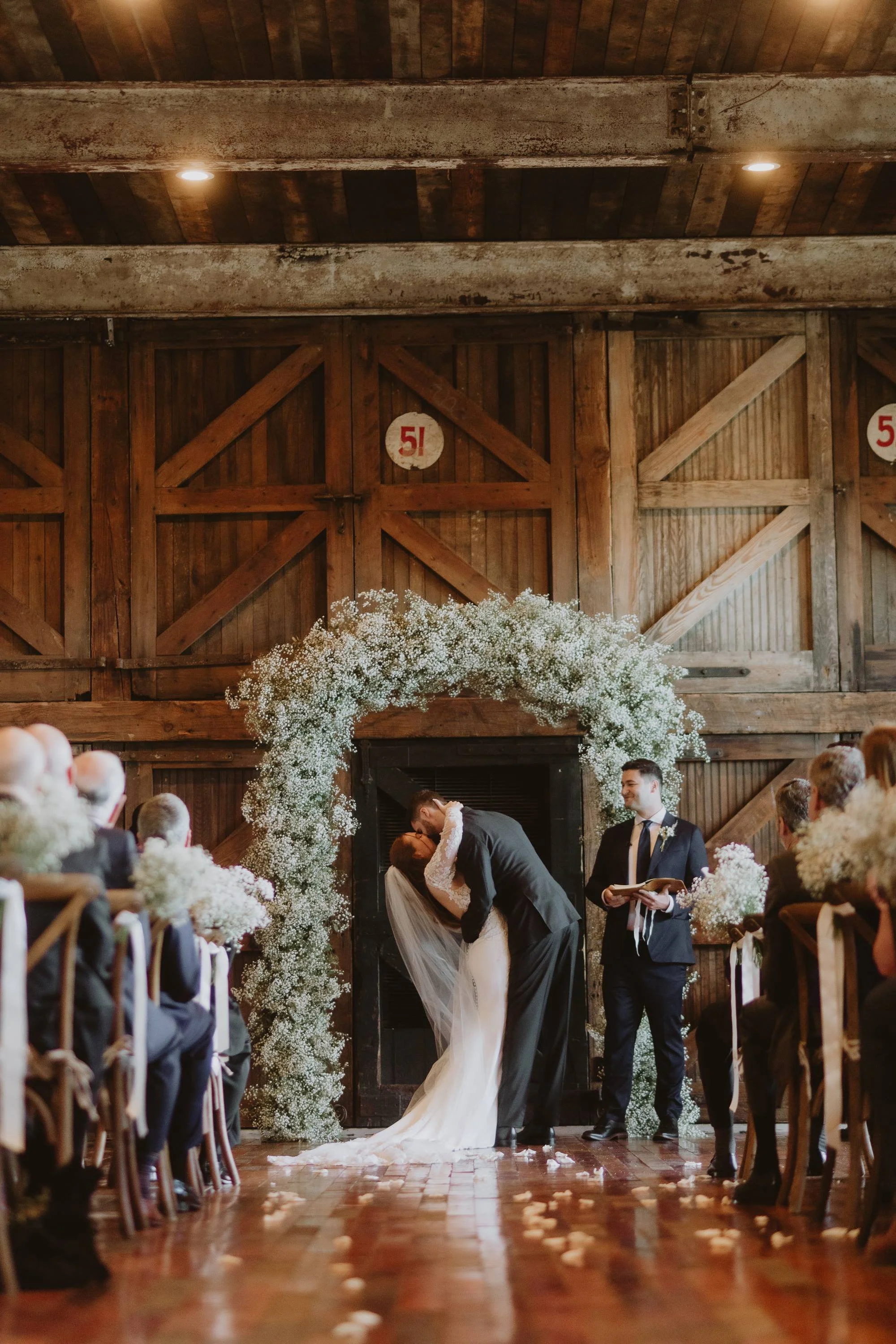 couple kiss floral arch during a wedding ceremony in the lakeside room at the Jefferson Oxford