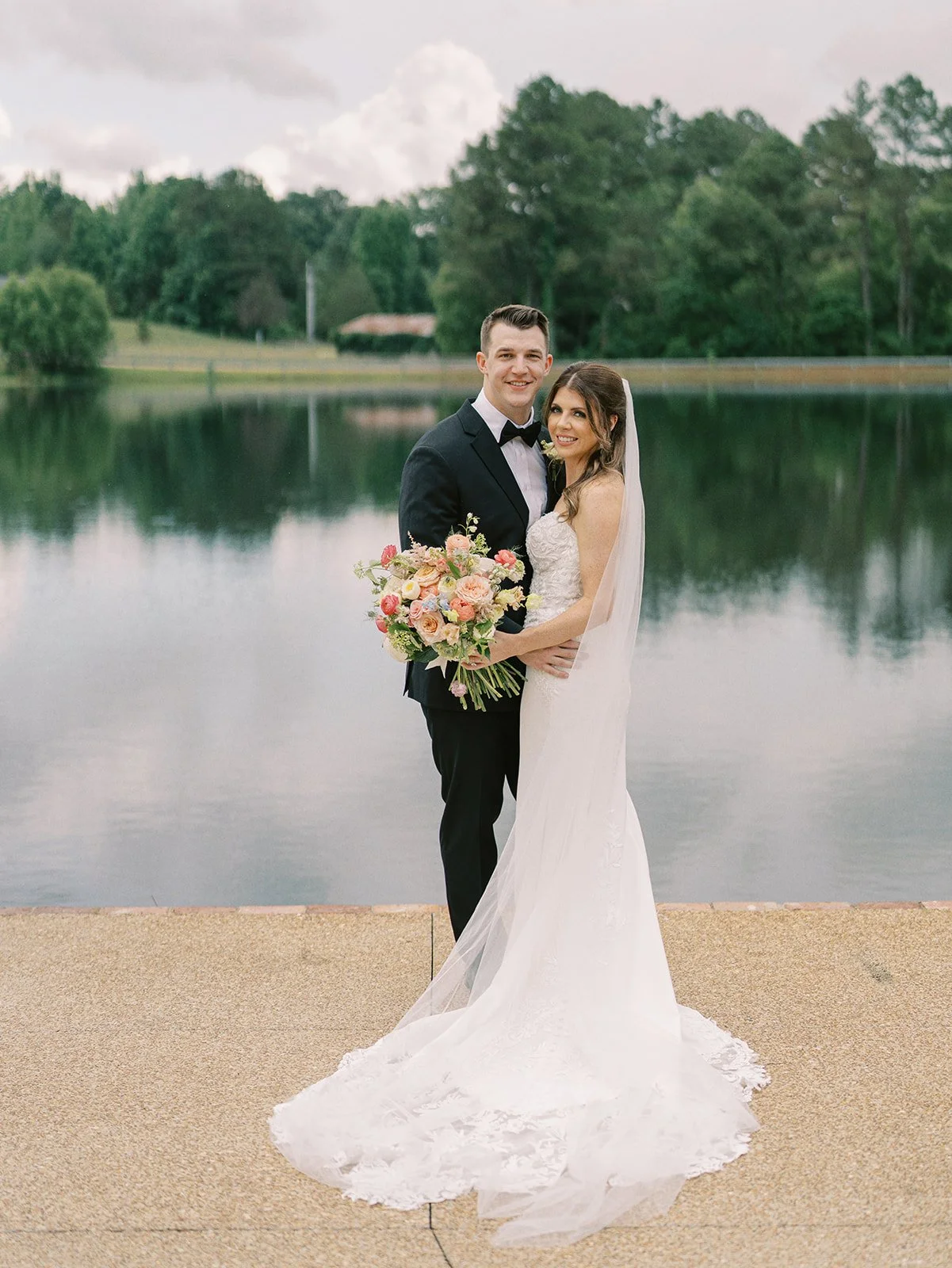 bride and groom with bouquet after wedding ceremony along lake at Jefferson Oxford