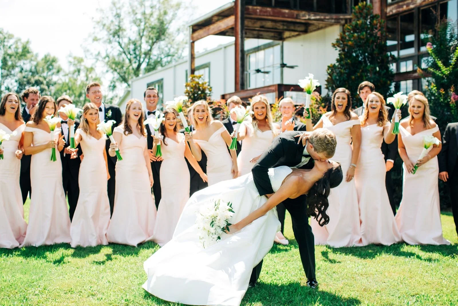 couple kissing with bridal party on lawn at The jefferson Oxford MS