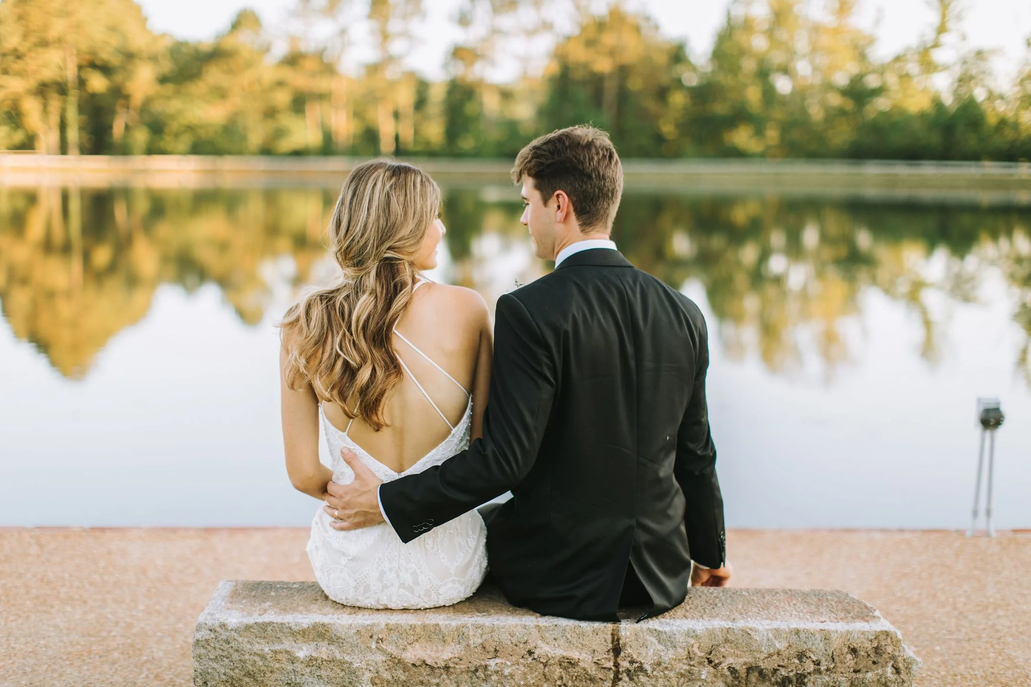 bride and groom sitting on lakefront bench at the Jefferson Oxford MS