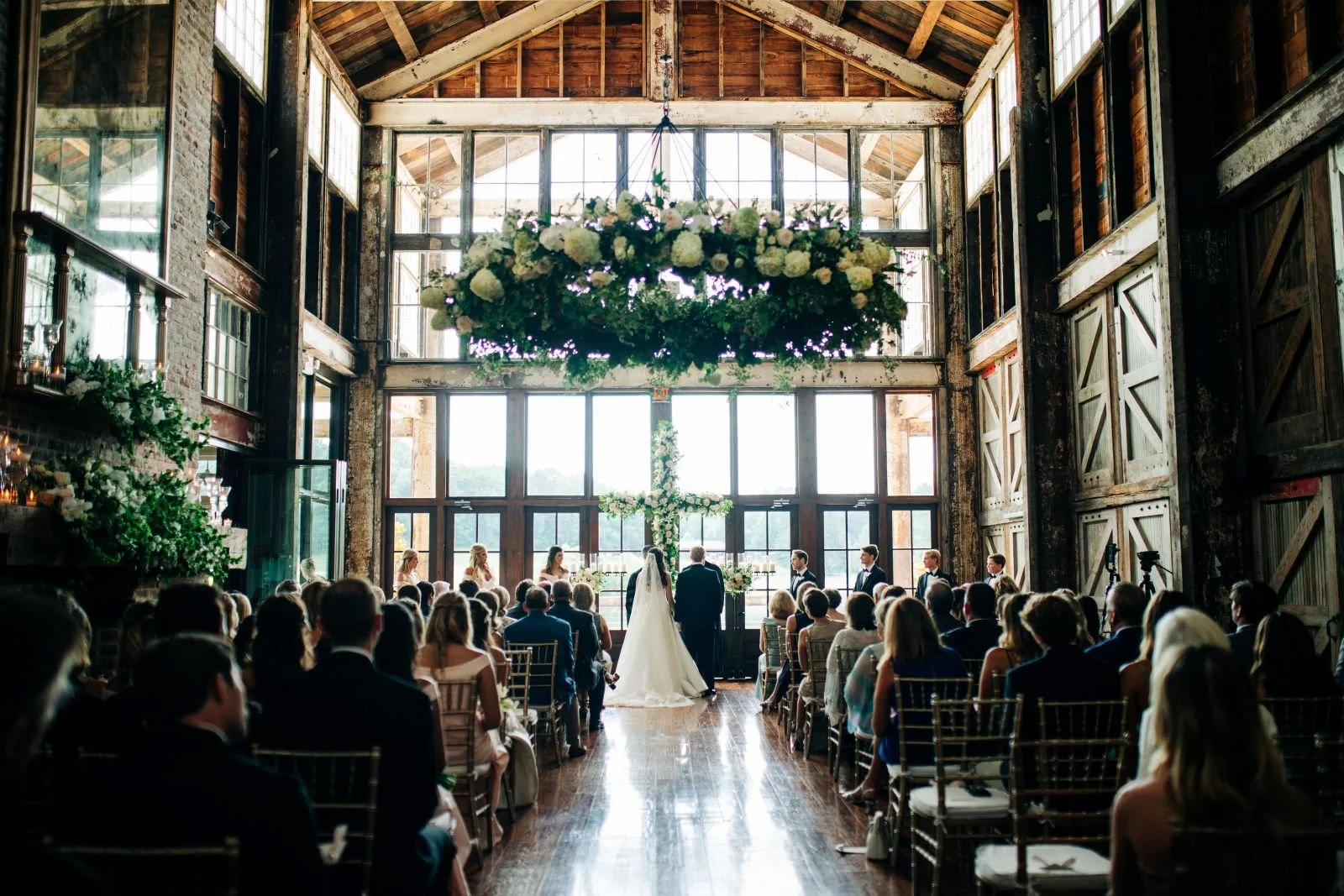 bride & groom during Faulkner Room wedding ceremony with floral chandelier at Jefferson Oxford