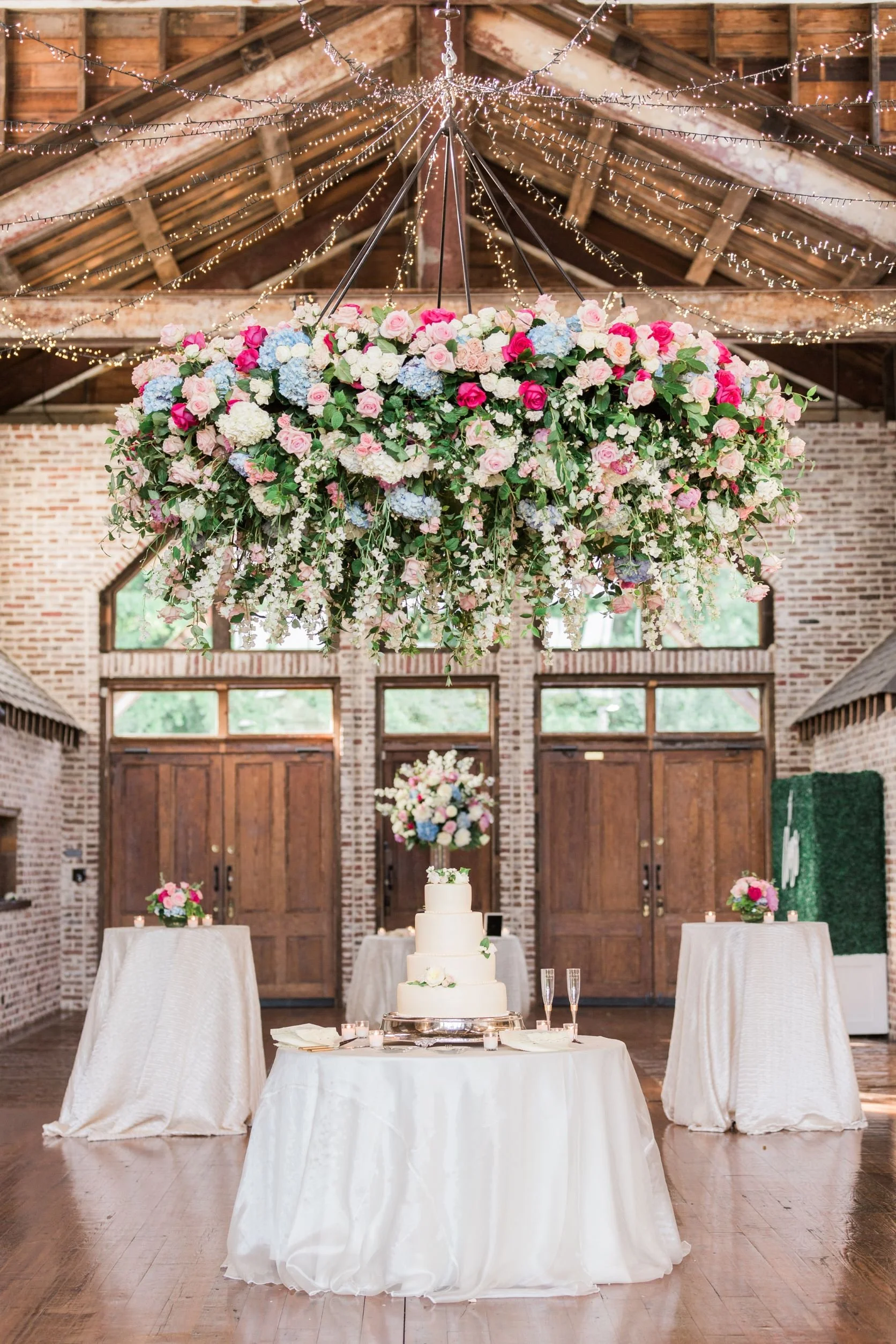 colorful floral chandelier hanging over bride's cake in faulkner room at the jefferson oxford