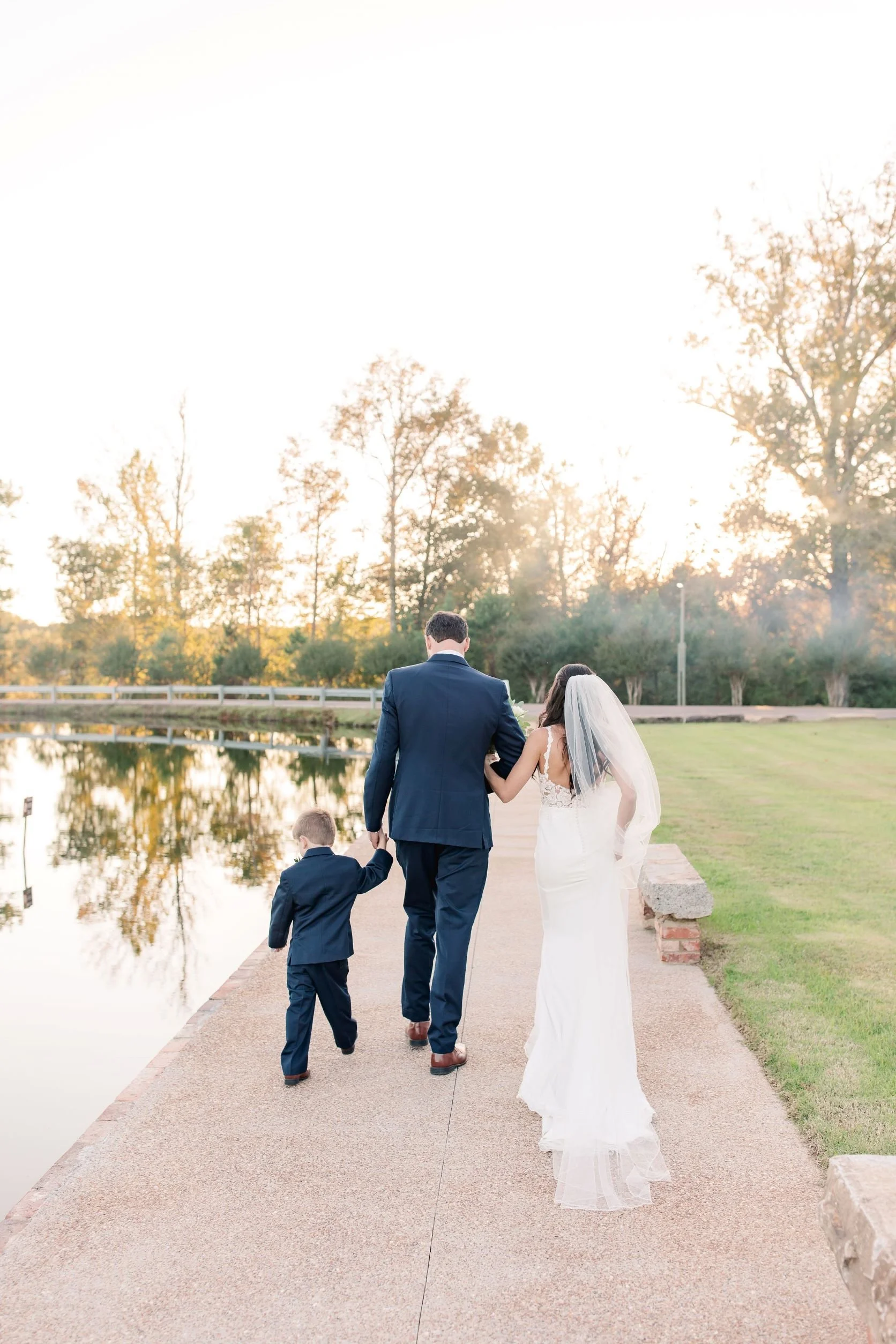 couple with son along lakefront walkway leaving outdoor wedding ceremony Jefferson Oxford