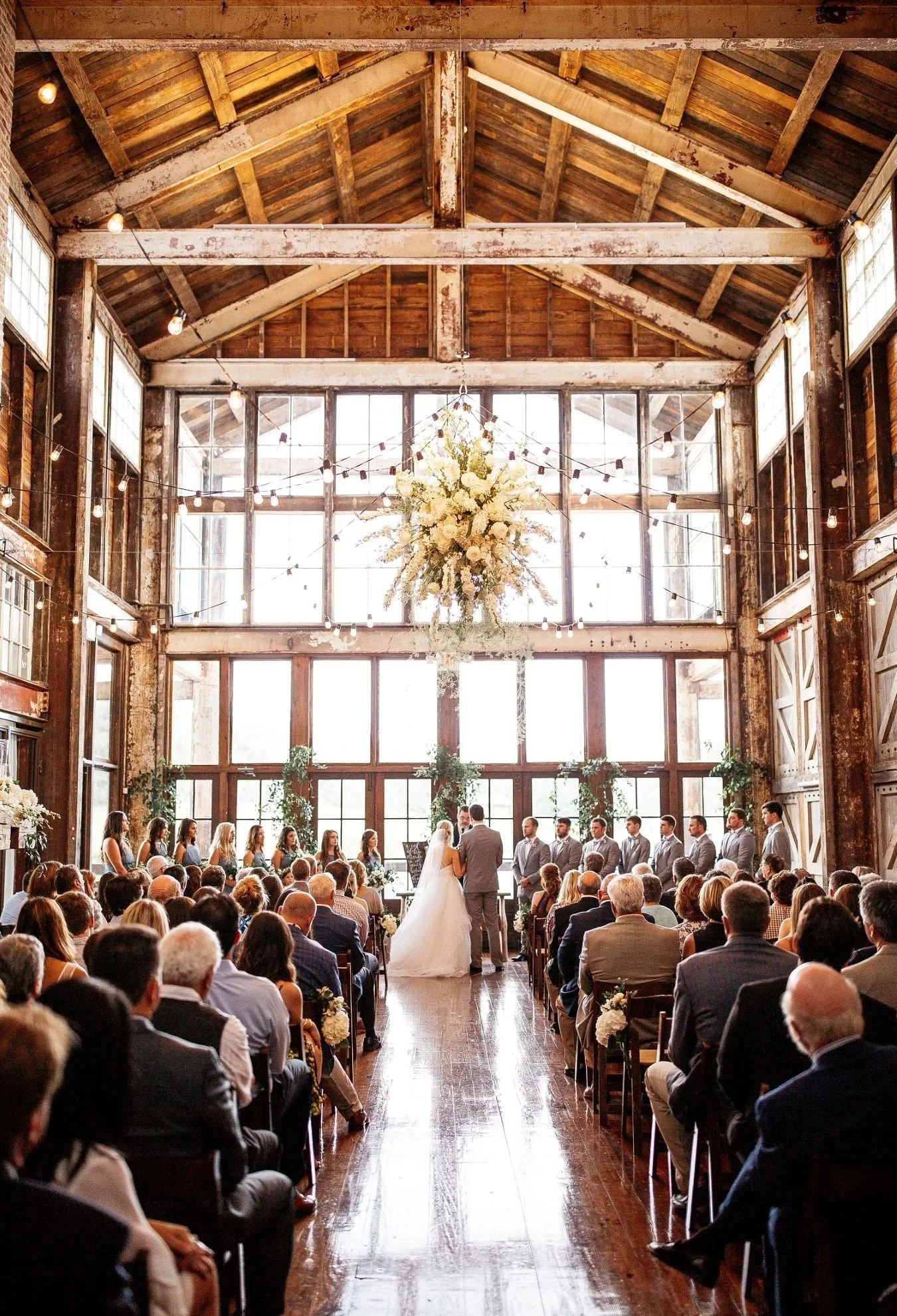 couple in Faulkner Room wedding ceremony with floral chandelier at Jefferson Oxford